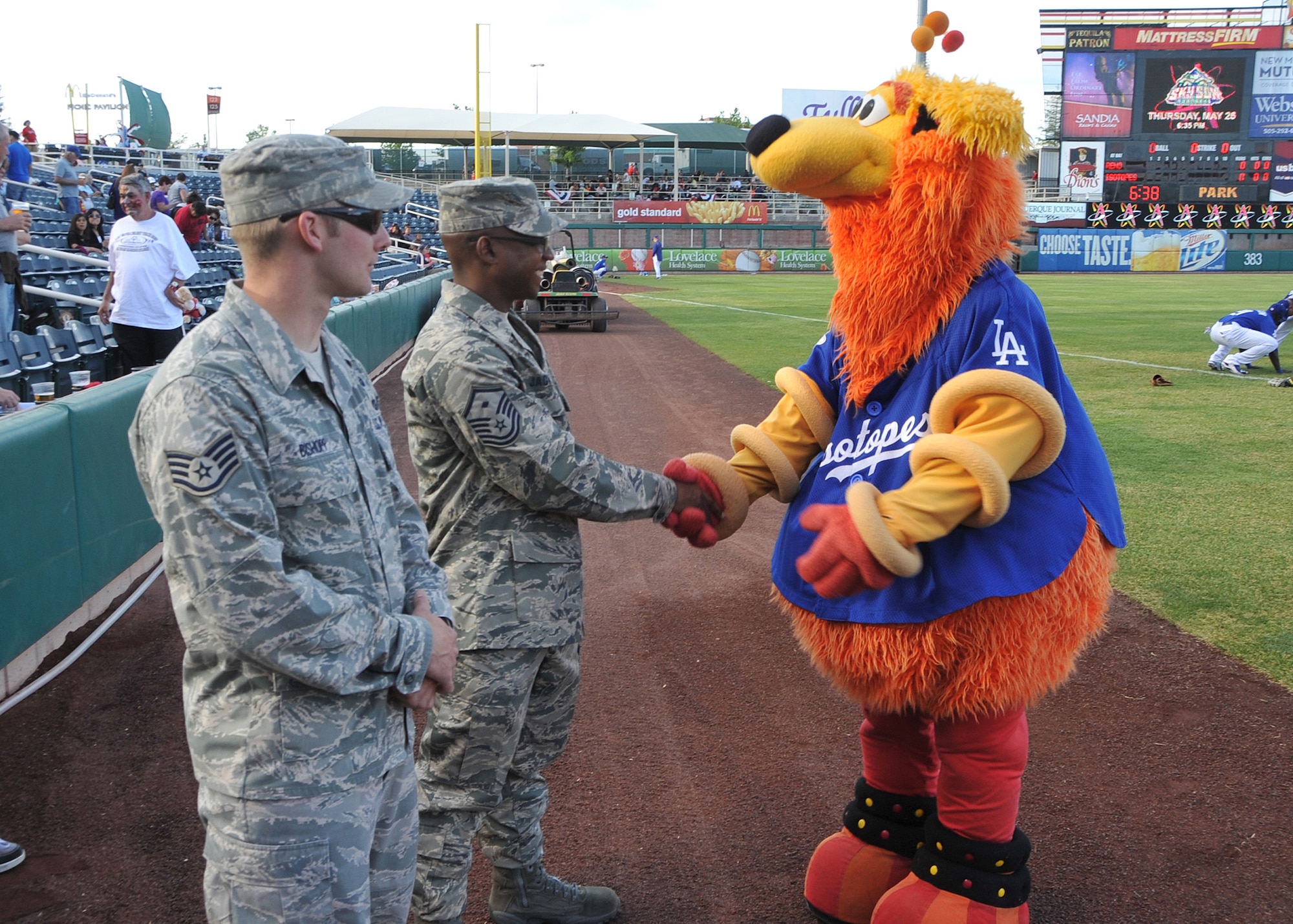 Albuquerque Isotopes mascot “Orbit” shook hands with Master Sgt. Leslie Jackson, 58th Special Operations Wing, center, and Staff Sgt. Jordan Bishopp, 377th Explosive Ordnance Disposal Flight, before they stepped onto the field to throw the first pitch May 21 during Military Appreciation Night. 

