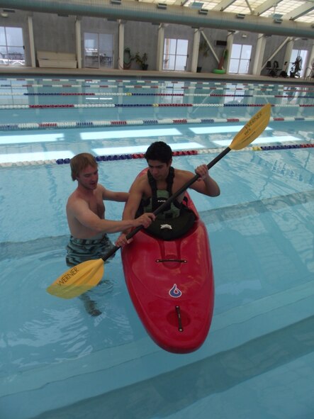 Jeff Harris, Outdoor Recreation Program Adventurer, demonstrates paddling techniques to Phillip Atencio, Outdoor Recreation lifeguard, at the indoor pool May 19.