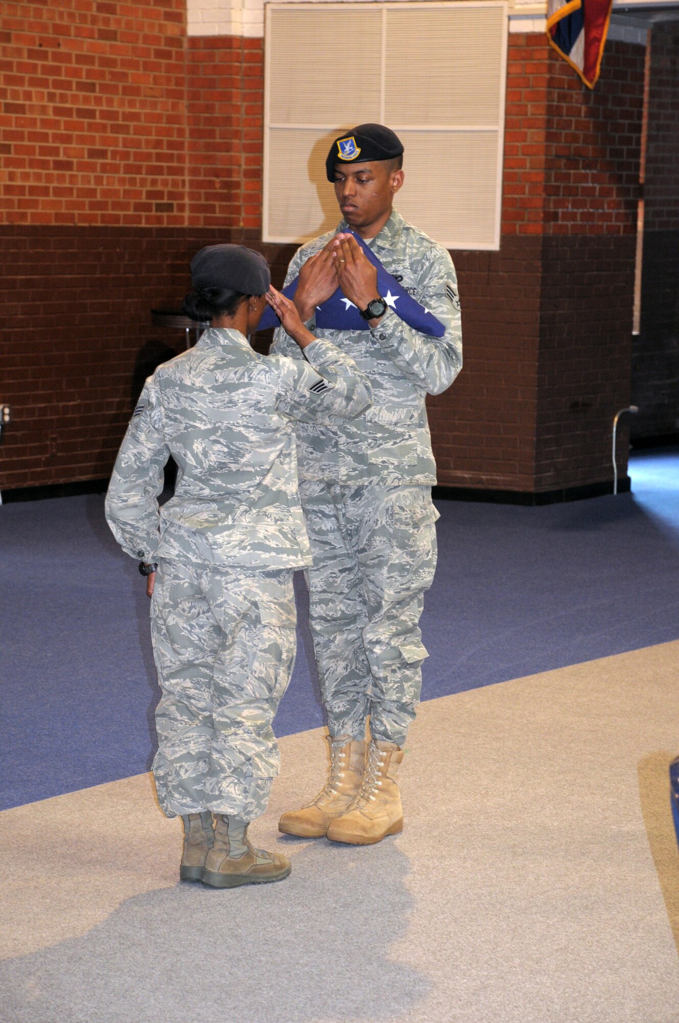 A member of the 90th Security Forces Group salutes the flag during a flag folding ceremony performed at retreat for the National Police Week observance held in the Fall Hall Community Center May 20.  (U.S. Air Force photo by Matt Bilden)