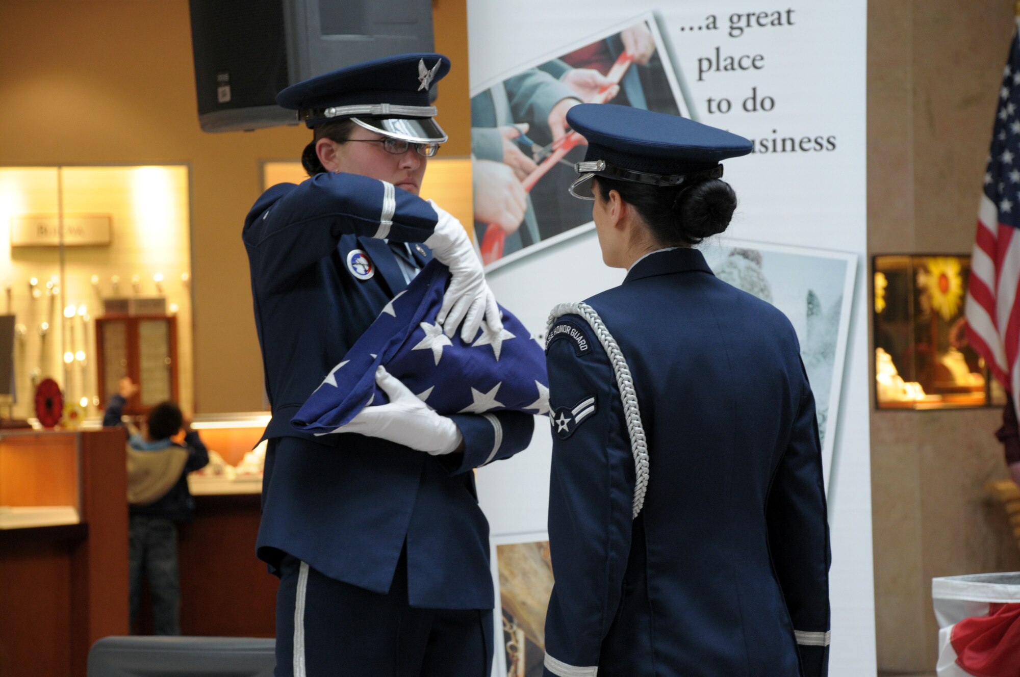 Airman 1st Class Hailey Snyder, 90th Security Support Squadron, and Airman 1st Class Maggie Green, 90th Medical Operations Squadron, perform a flag ceremony in Cheyenne's Frontier Mall during an Armed Forces Day ceremony Saturday. (U.S. Air Force photo by Blaze Lipowski)