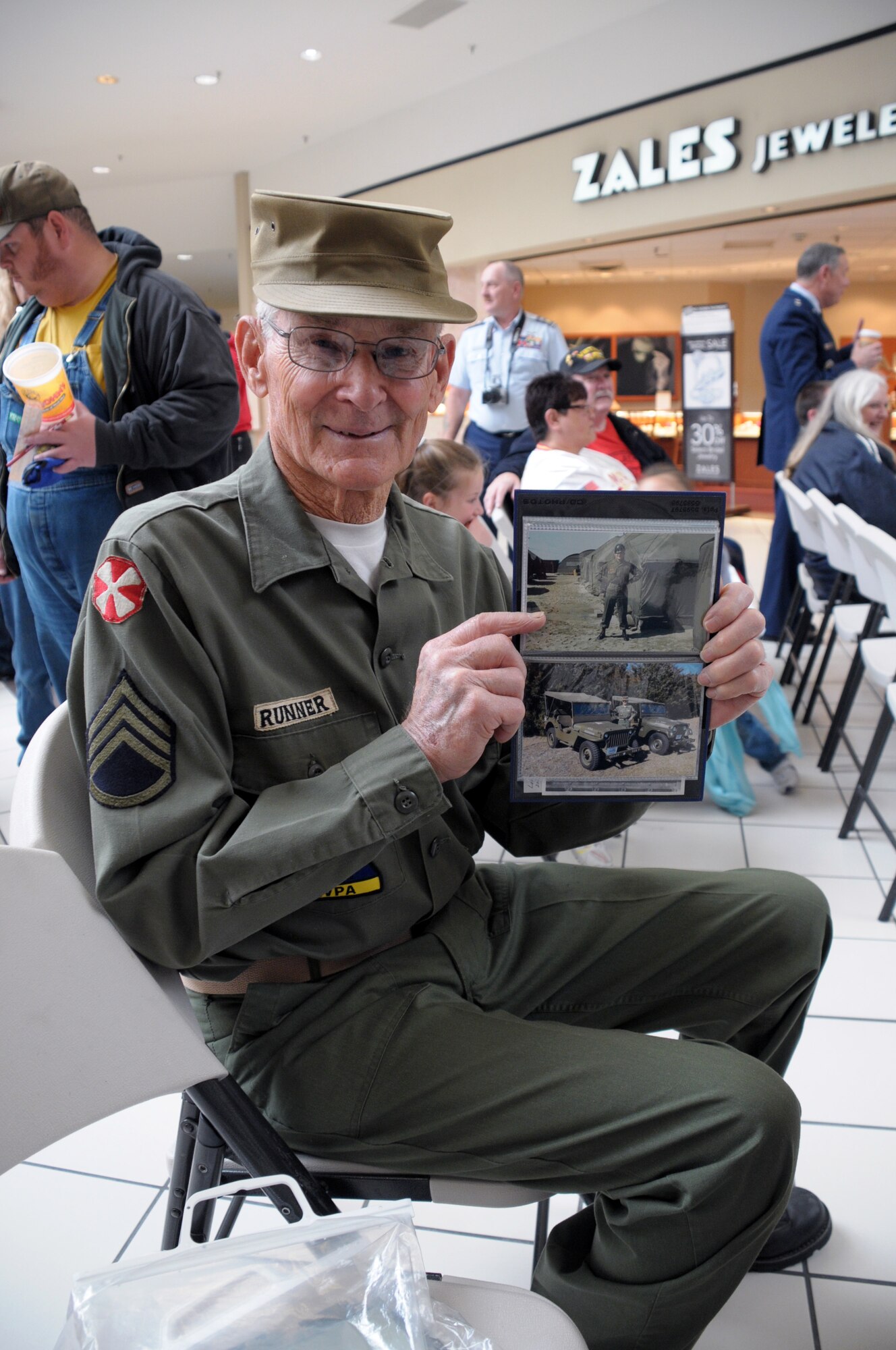 Retired Army veteran Bob Runner shows "then and now" photos from his time in the service before the Armed Forces Day ceremony at the Frontier Mall Saturday. (U.S. Air Force photo by Blaze Lipowski)