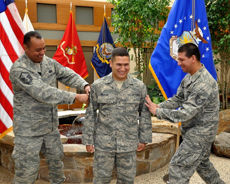 Senior Airman Agustin Salazar braces and smiles as Master Sgt. Edwin Del Castillo and Tech. Sgt. Adri Medina-Sanchez help him to tack on staff sergeant stripes during a promotion ceremony May 26,2011 at the Charles C. Carson Center for Mortuary Affairs. Sergeant Salazar is deployed to Air Force Mortuary Affairs Operations from the 149th Fighter Wing Air National Guard at Lackland Air Force Base, Texas. (U.S. Air Force photo/Van N. Williams)