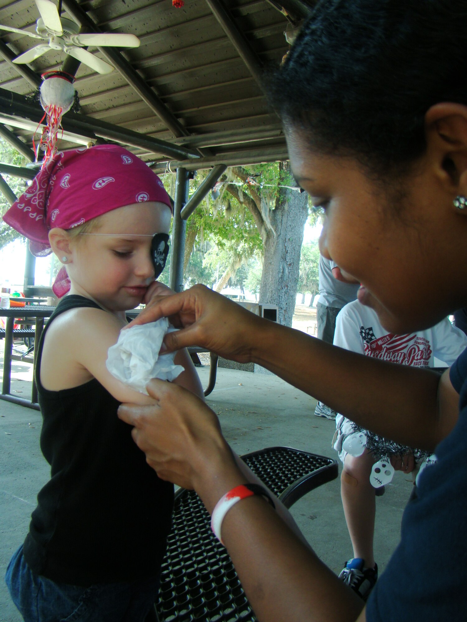 Kaitlyn Dunn, 3, is tattooed by Senior Airman Shelly Meczywor, 81st Force Support Squadron, at the pirate party for families of deployed members in marina park Saturday.  Kaitlyn’s parents are Staff Sgt. Peter and Janette Dunn, 338th Training Squadron. Sergeant Dunn is currently deployed to Afghanistan.  (U.S. Air Force photo by Airman 1st Class Heather Heiney) 