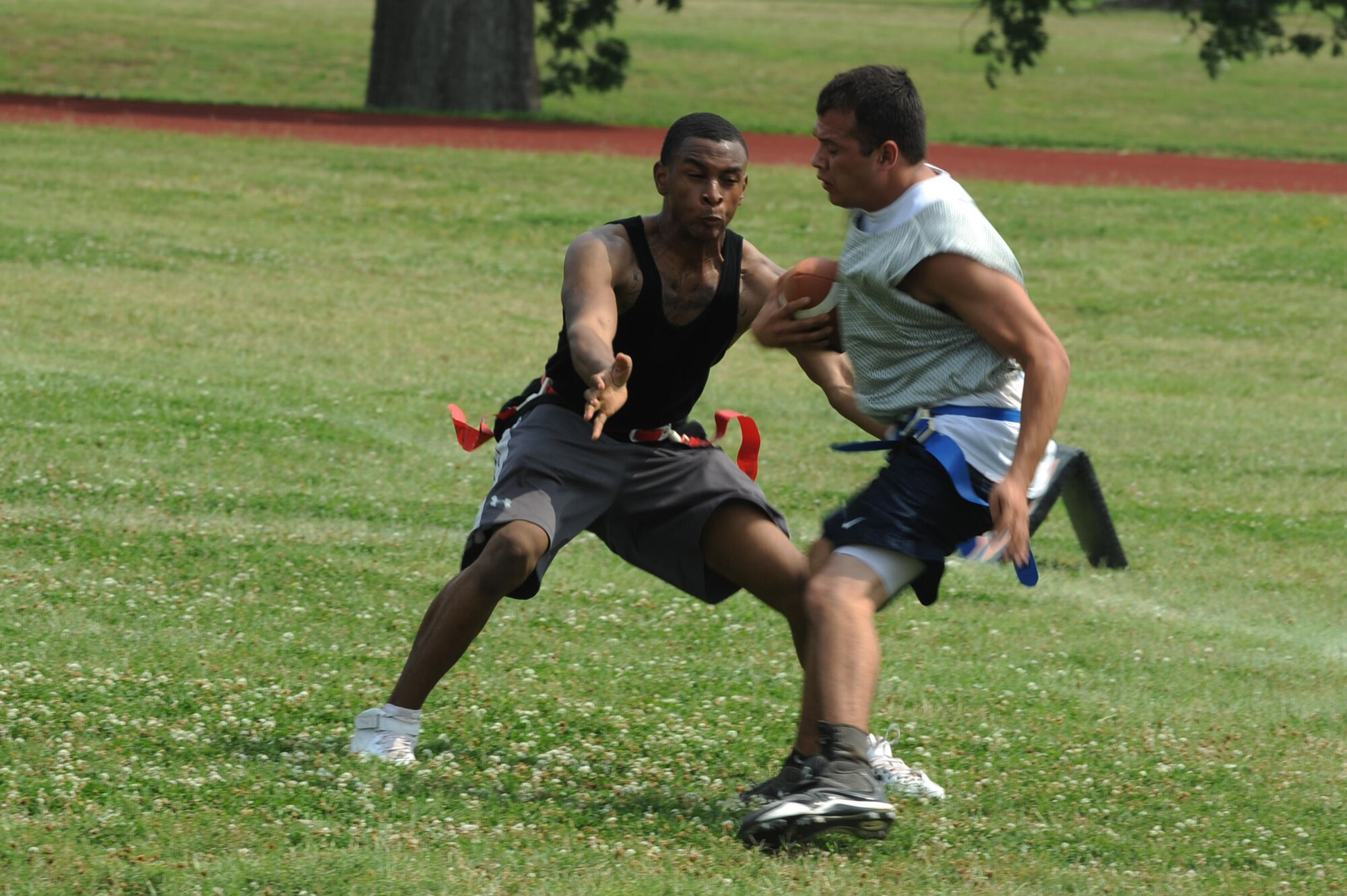 An Airman from the 2nd Operations Support Squadron runs the football while an Airmen from the 2nd Civil Engineer Squadron plays defense during the 2nd Bomb Wing Sports Day football tournament on Barksdale Air Force Base, La., May 25. Sports Day is comprised of various competitive athletic events to help promote physical fitness. (U.S. Air Force photo/Airman 1st Class Micaiah Anthony) (RELEASED)