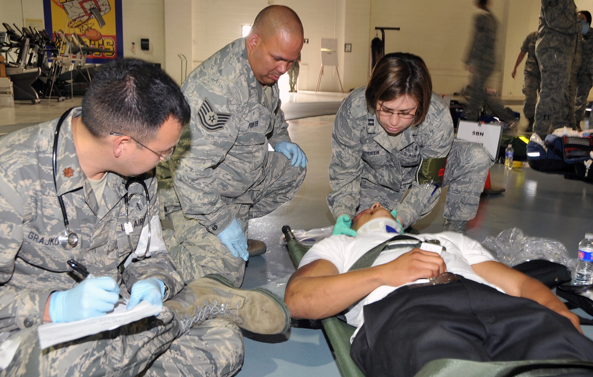 OFFUTT AIR FORCE BASE, Neb. --Maj Eric Grajkowski from the 55th MDG documents from the side as Capt Deborah Lundeen performs procedures to a simulated wounded victim while TSgt Anthony Porter from the MDOS watches next to her. Offutt Afb performed a national level exercise for 2011 on May 19 at the field house. Many participants were on hand for the NDMS Exercise, including many base agencies from Omaha simulating real life transporting of medical personel and victims acting out and responding giving medical care in case of a community emergency. U.S. Air Force Photo by Jeff W. Gates. 