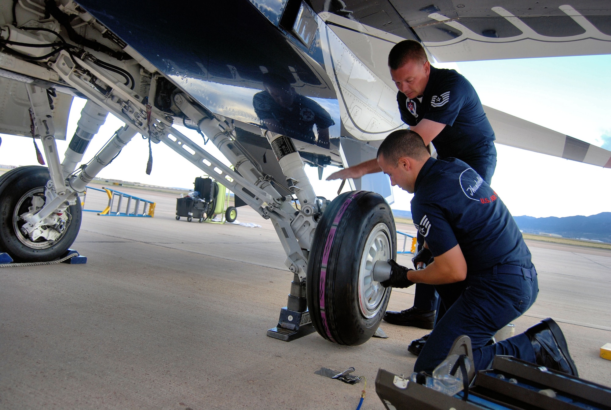 PETERSON AIR FORCE BASE, Colo. –Tech. Sgt. Adam Porter, avionics technician for the Air Force Thunderbirds, and Staff Sgt. Luke Miller, aircraft maintenance for the Air Force Thunderbirds, attach a new tire to one of the Thunderbird’s six F-16s on Peterson Air Force Base, May 23, 2011. The Thunderbirds landed at Peterson AFB for the U.S. Air Force Academy graduation where they performed a flyover and demonstration as part of the 2011 graduation ceremony, held May 25. (U.S. Air Force photo/Airman 1st Class Jessica Hines) 