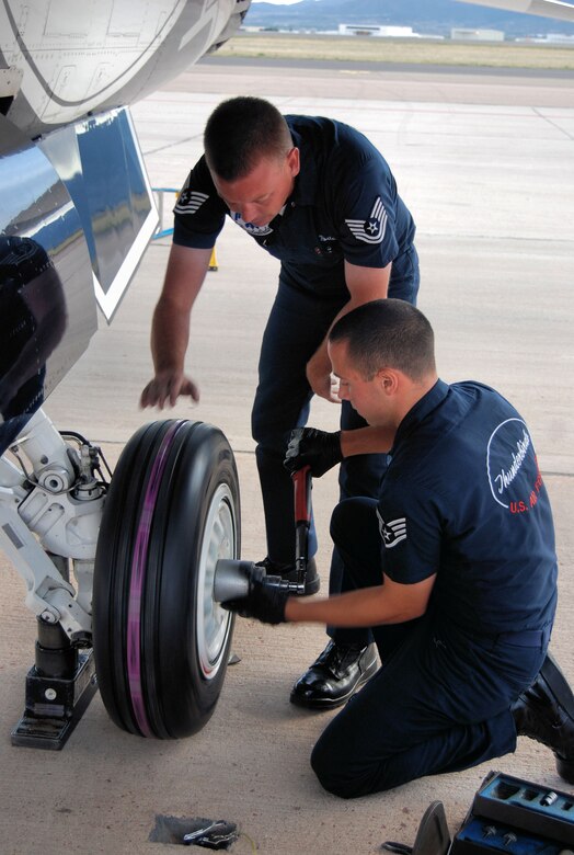 PETERSON AIR FORCE BASE, Colo. –Tech. Sgt. Adam Porter, avionics technician for the Air Force Thunderbirds, and Staff Sgt. Luke Miller, aircraft maintenance for the Air Force Thunderbirds, attach a new tire to one of the Thunderbird’s six F-16s that were on Peterson Air Force Base, May 23, 2011. The Thunderbirds landed at Peterson AFB for the U.S. Air Force Academy graduation where they performed a flyover and demonstration as part of the 2011 graduation ceremony, held May 25. (U.S. Air Force photo/Airman 1st Class Jessica Hines) 