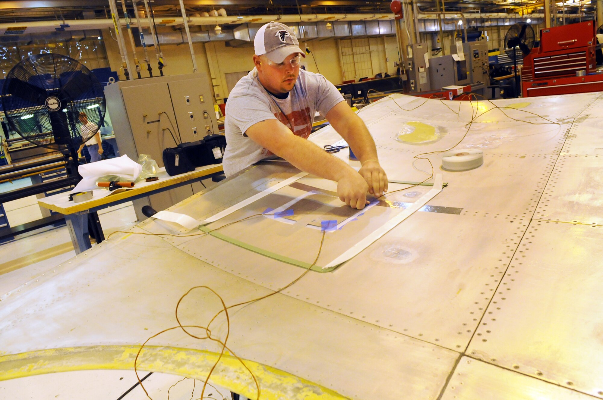 Steven Sama, sheet metal mechanic, lays out a metal bond repair on a C-5 flap. U. S. Air Force photo by Sue Sapp