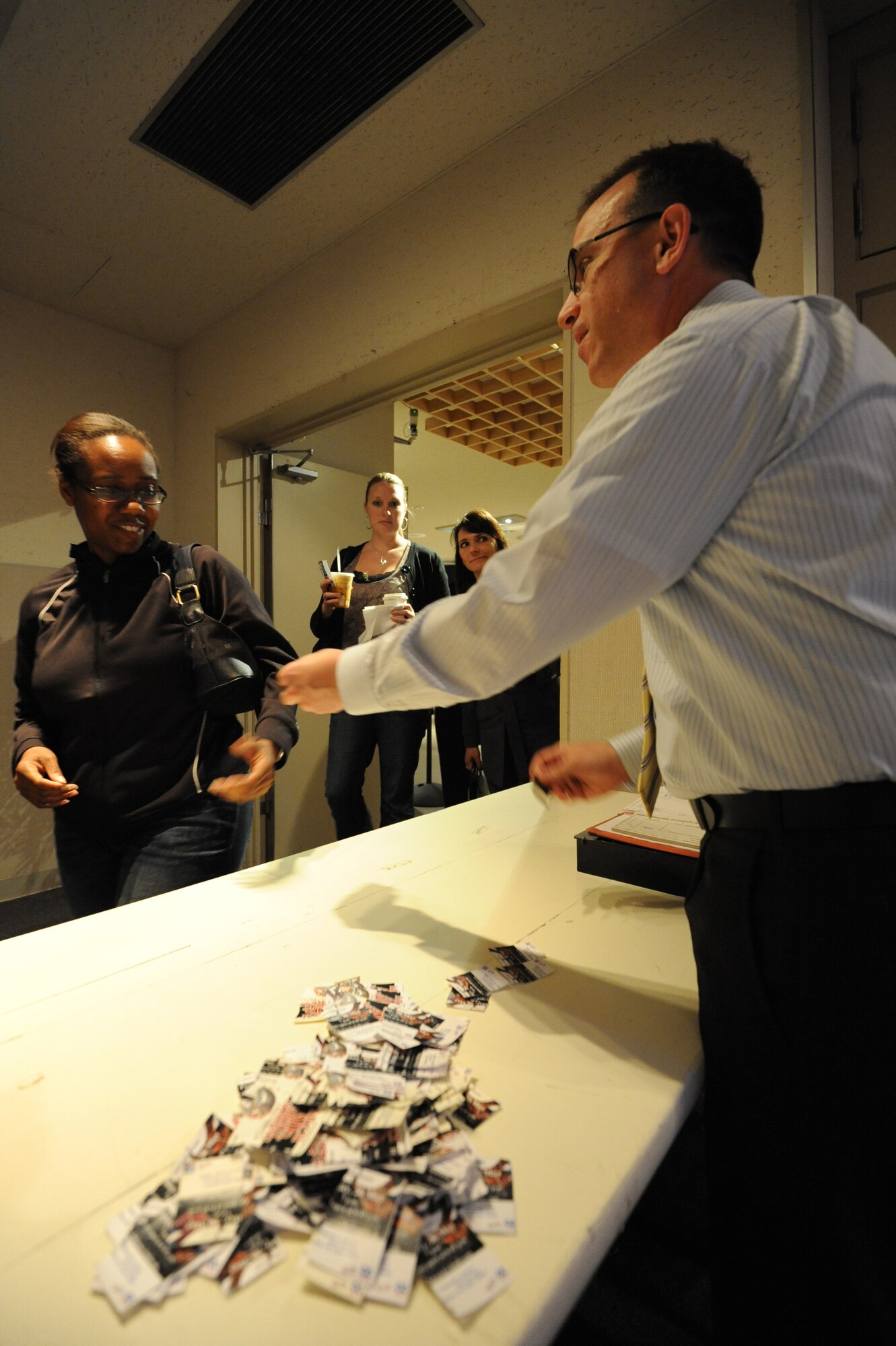 MISAWA AIR BASE, Japan -- Capt. Strysan Murrell, 35th Maintenance Operations Squadron operations officer, reaches for her ticket stub from Michael Wadkins, 35th Force Support Squadron community center director, upon entering the Mokuteki Community Center May 20.  Since the earthquake on March 11, the Mokuteki Community Center was used as the control center for Misawa Helps, but has now reopened to the public.  (U.S. Air Force photo Staff Sgt. April Quintanilla)