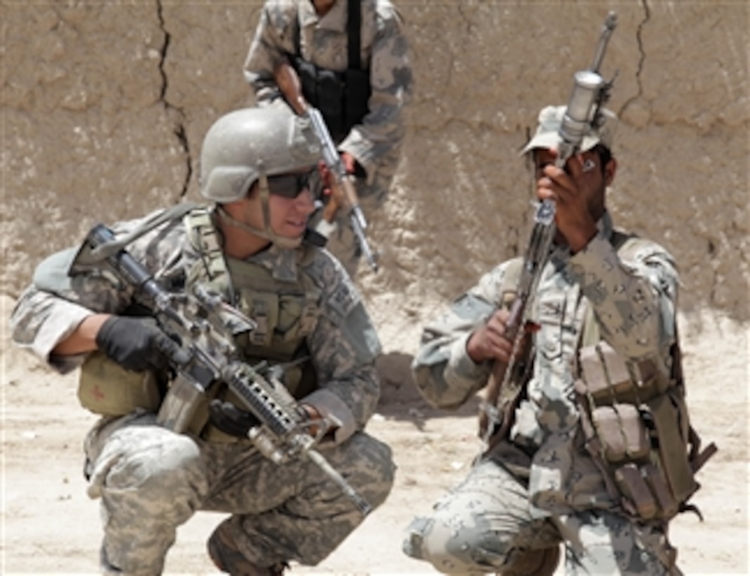 A U.S. Army soldier with Charlie Company, 1st Squadron, 38th Cavalry Regiment, 525th Battlefield Surveillance Brigade, and an Afghan counterpart check weapons before searching homes for explosives in Khwazha Bana village, Kandahar province, Afghanistan, on May 9, 2011.  