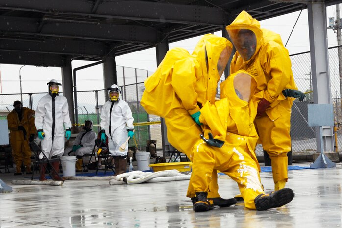 Two station personnel drag their injured team memebr to a decontamination site during an Introduction to Hazardous Response Course training scenario taught by HazTrain at the tarmac here May 26. The course participant being dragged faked being injured during the training scenario to test his teamates' ability to react to the situation.