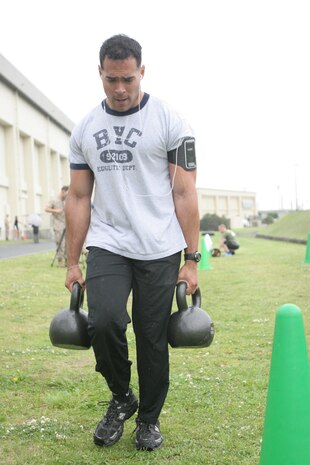 Anthony Sanz performs the farmer’s walk with 70 pound kettlebells during the Fitness Fallout here May 27. Sanz took second place in the men’s division. The event consisted of exercises ranging from the farmer’s walk, thrusters, kettlebell swings, box jumps and tire flips.