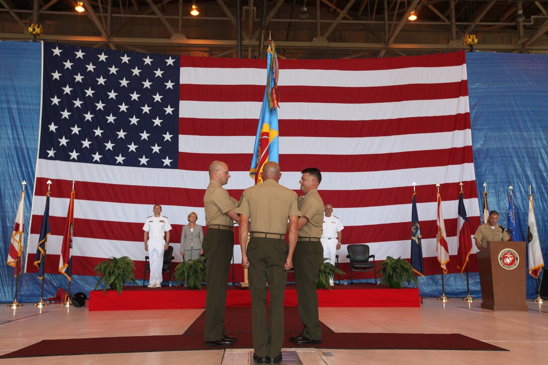 Col. L. Scott Loch passes on the command colors of Fleet Readiness Center East to Col. Mitchell A. Bauman during the change of command ceremony inside one of the FRC East hangars May 27.