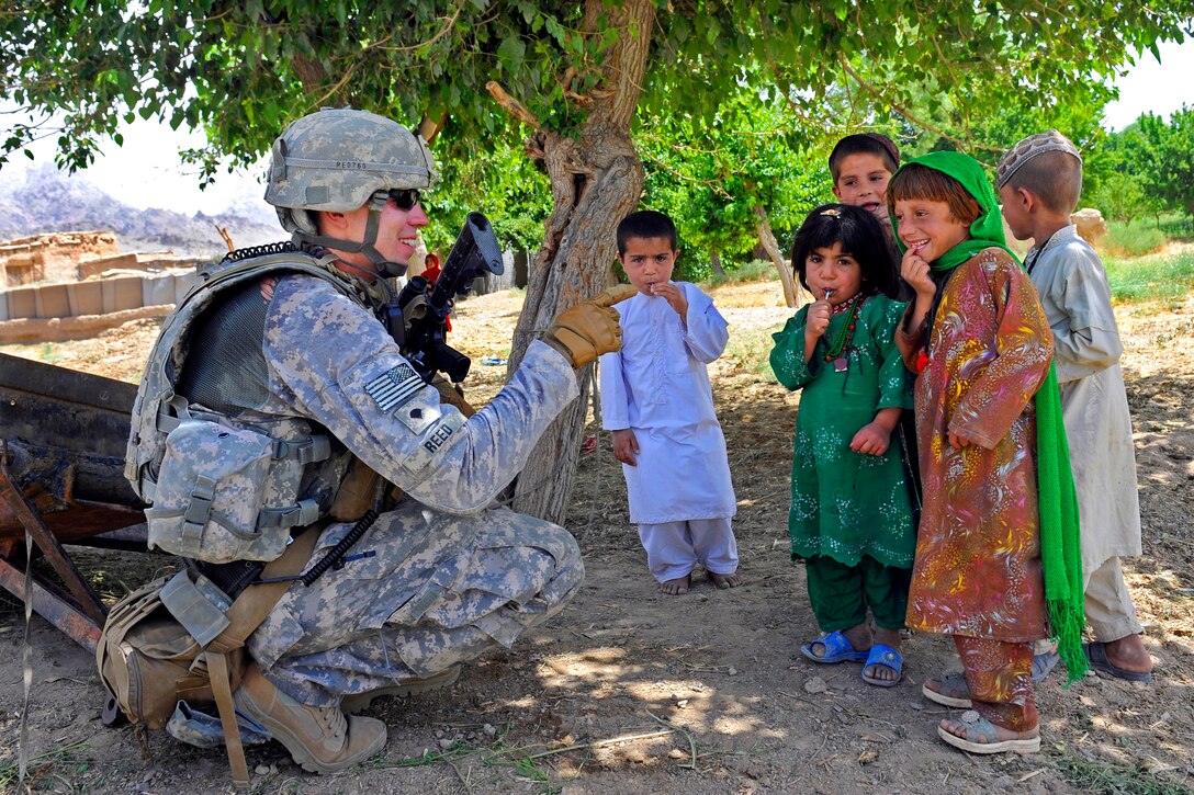 U.S. Army Spc. Jonathan Reed entertains a group of children as members of Provincial Reconstruction Team Zabul meet with elders from Deh Afghanan village, Afghanistan, May 27, 2011. Reed is a medic assigned to the team.