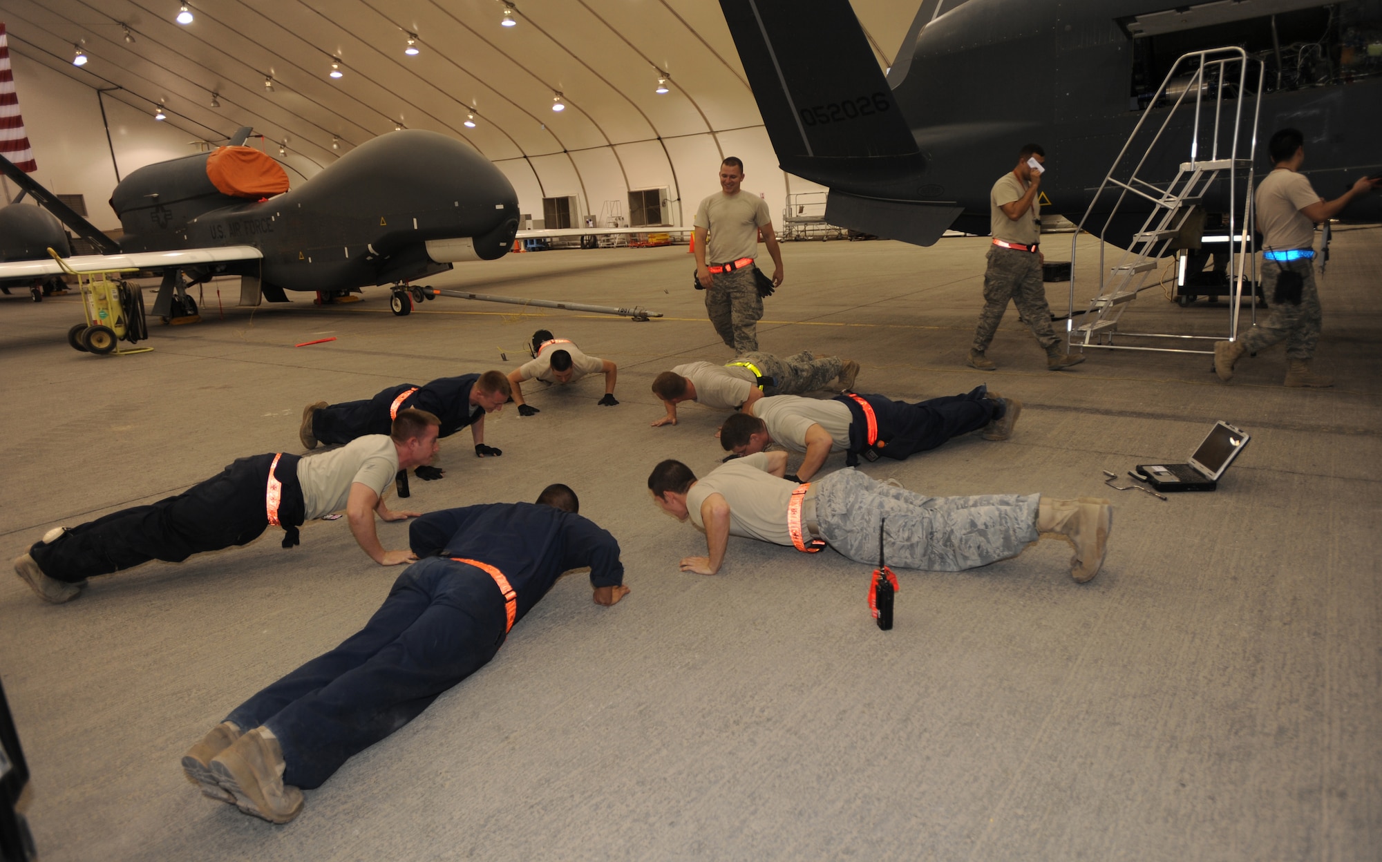Continuing a 380th Expeditionary Aircraft Maintenance Squadron crew chief tradition, these seven execute 26 push-ups which is equivalent to this RQ-4B Global Hawk’s last two tail number digits May 11, 2011, in Southwest Asia. As in most Air Force aircraft maintenance squadrons, this is a way of christening the brand new addition to the 380th Air Expeditionary Wing. (U.S. Air Force photo by Senior Airman Maynelinne De La Cruz)     