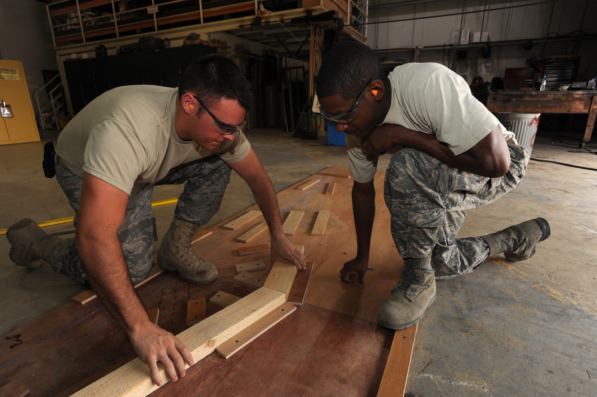 Senior Airman Chris Fehringer (left) and Staff Sgt. John Brown, both from the 380th Expeditionary Civil Engineer Squadron, assemble parts for a Fire Suppression Unit System pump house roof April 18, 2011, in Southwest Asia. Civil engineers work 50 to 75 projects a week from building new facilities to adjusting doors.  (U.S. Air Force photo by Senior Airman Maynelinne De La Cruz)  