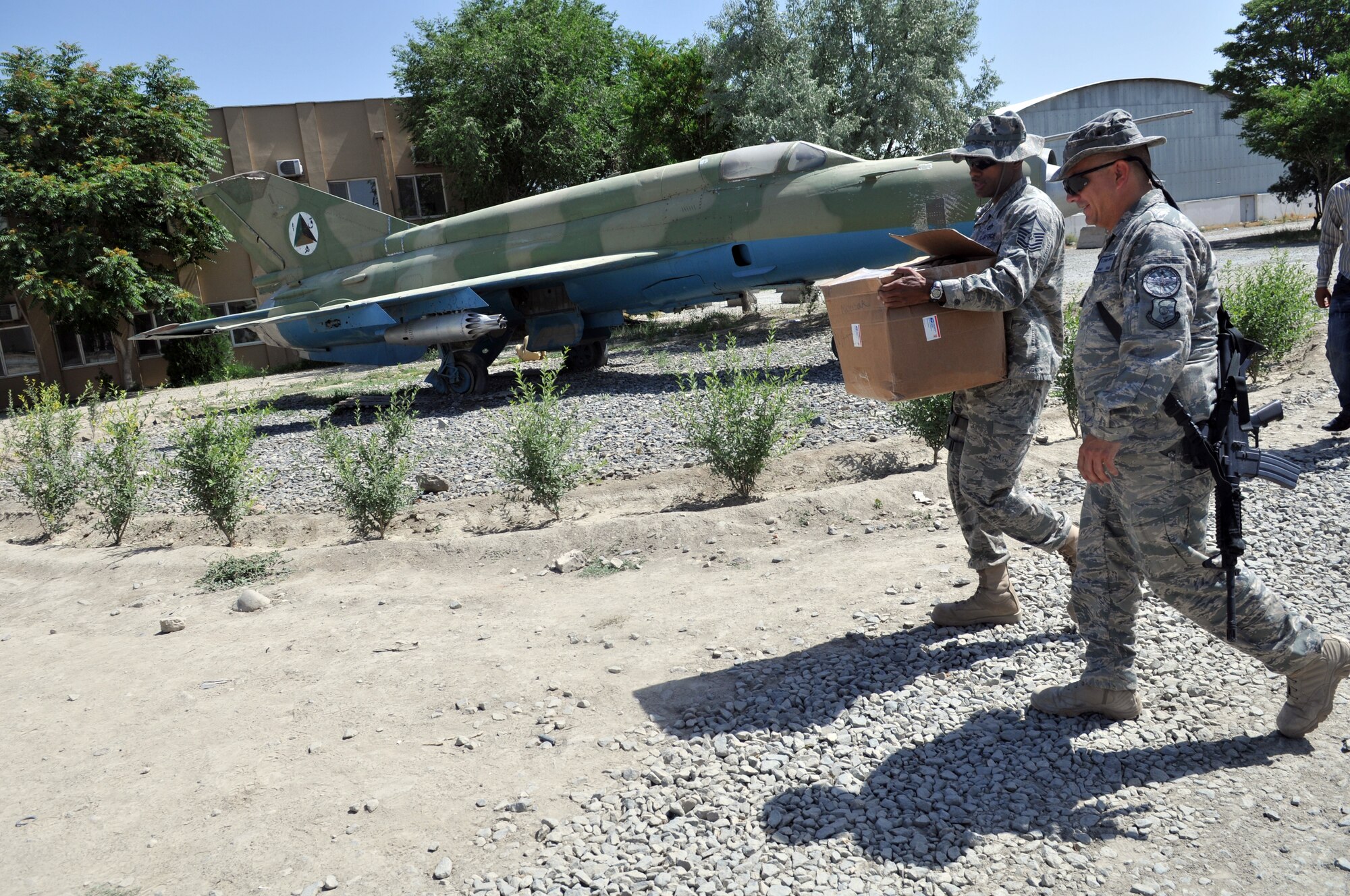 KABUL, Afghanistan -- Master Sgt Dion Bullock, a 738th Air Expeditionary Advisory Squadron firefighter advisor, carries a box of Nomex fire protection hoods while walking with Master Sgt. Edward Nowak, 440th Air Expeditionary Advisory Squadron C-27 production superintendant advisor and volunteer firefighter, to the Afghan Air Force fire fighting training complex. The Nomex hoods were donated by the Robeson County Firefighters Association located in Parkton, N.C. (US Air Force Photo by Tech. Sgt. Brian E. Christiansen)