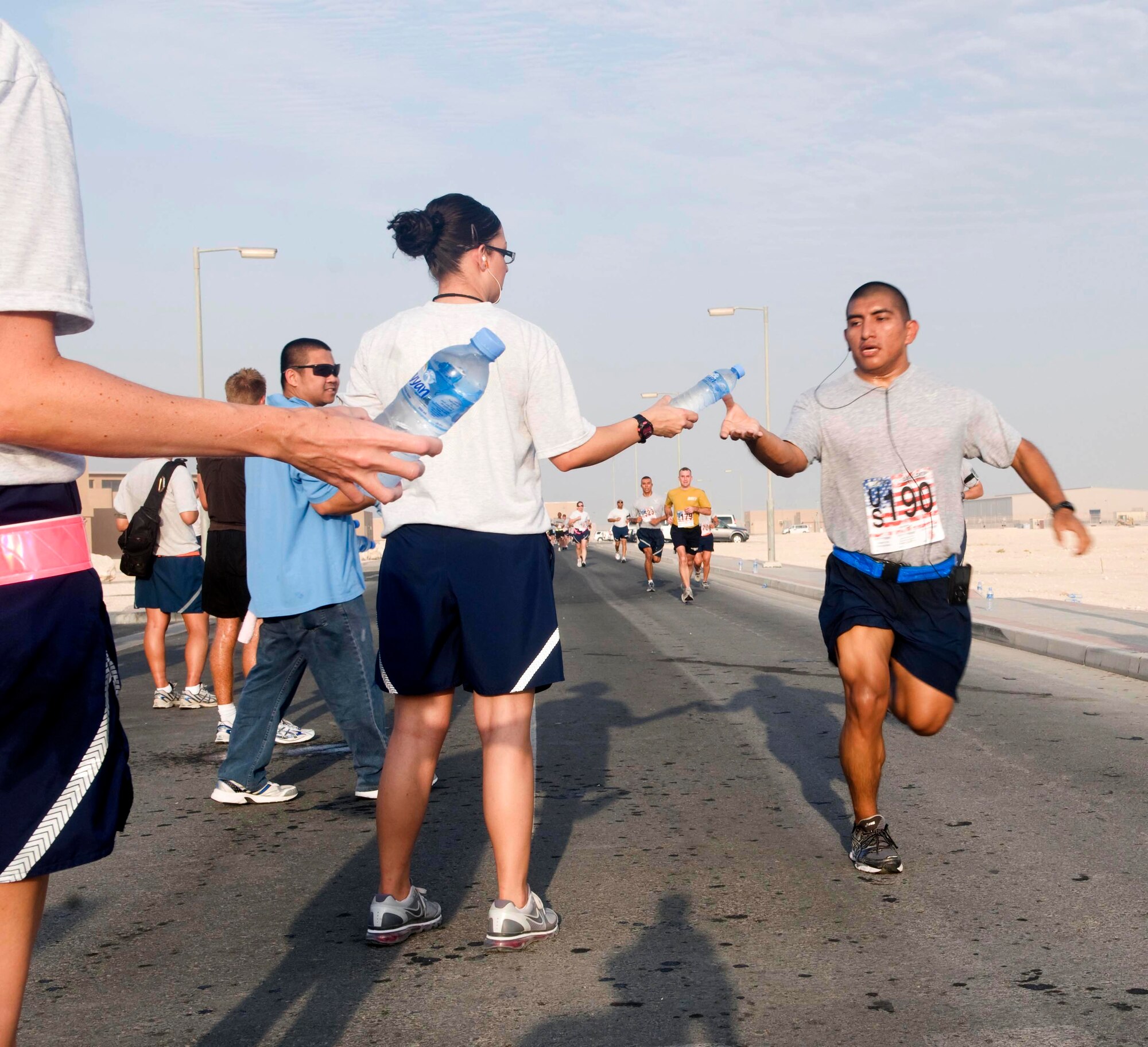 A deployed Airman reaches for a bottle of water while running in the Bolder Boulder 10K May 30, at an air base in Southwest Asia. (U.S. Air Force photo/Staff Sgt. Anthony Graham)