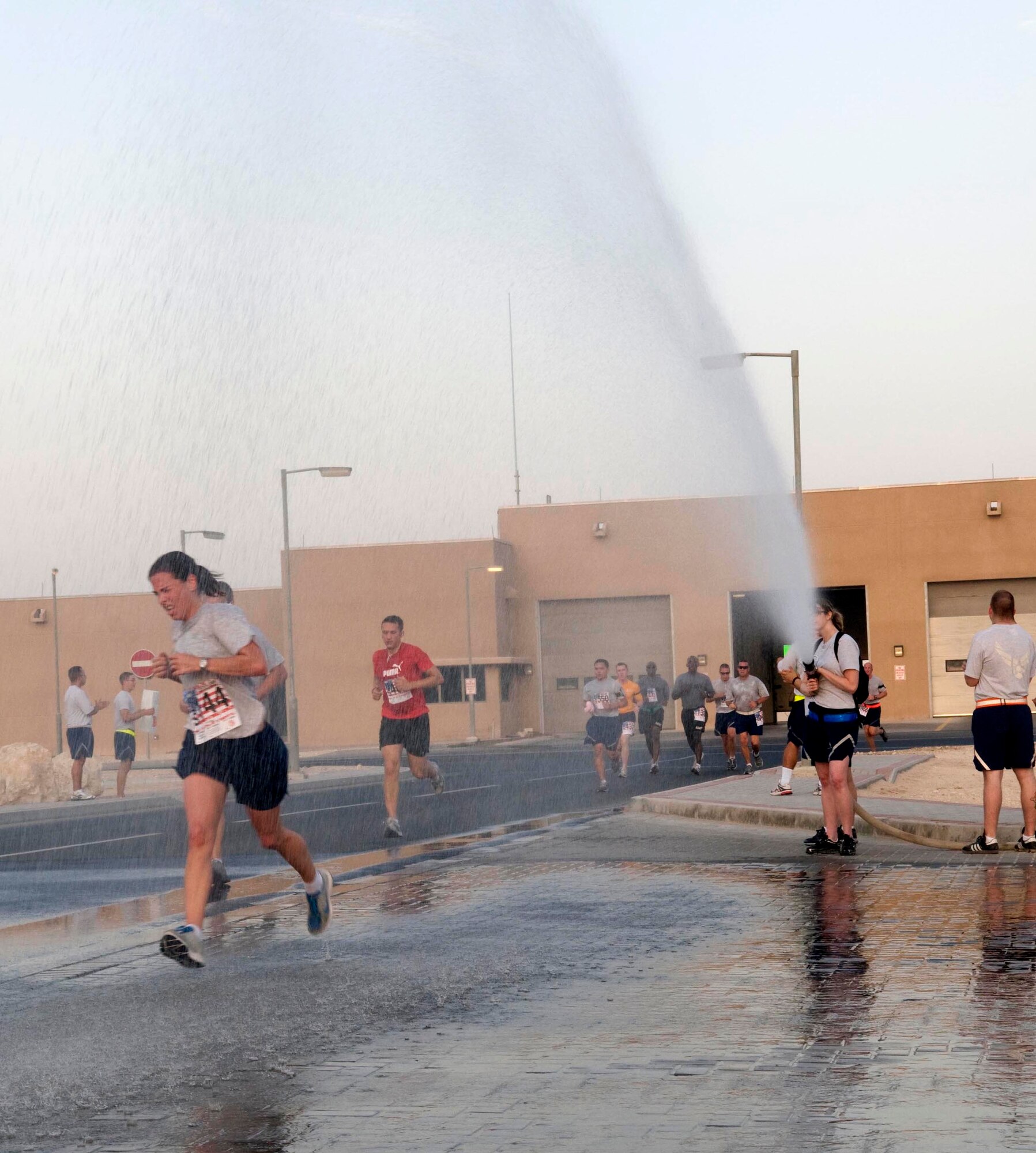 Runners cool off with the spray of a fire hose May 30 during the Bolder Boulder 10K run at a deployed location in Southwest Asia. More than 100 U.S. and coalition service members participated in the event. (U.S. Air Force photo/Staff Sgt. Anthony Graham)