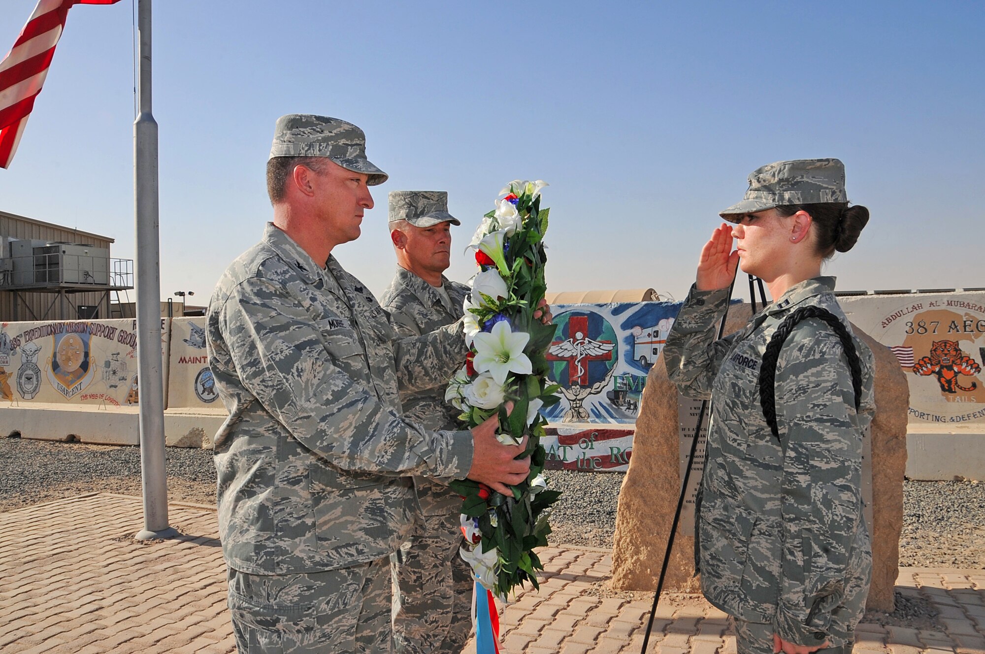 Colonel Patrick Mordente, 386th Air Expeditionary Wing commander, left, and Chief Master Sgt. Richard Turcotte, 386th command chief, receive the memorial wreath from Capt. Laura Nichols, a 386th Honor Guardsman, May 30 during a Memorial Day ceremony, which honored the fallen but not forgotten servicemembers. (U.S. Air Force photo by Senior Airman Cynthia Spalding)