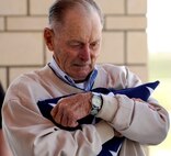 Edward Kooper, brother of 1st Lt. Clark Kooper, a U.S. Army Air Force pilot shot down during World War II, cradles a U.S. flag given to him by the Ellsworth Air Force Base, S.D. Honor Guard, at the Nebraska Veterans Cemetery, Alliance, Neb., May 27, 2011. Mr. Kooper was finally able to lay his brother to rest, more than 66 years after his plane was shot down. (U.S. Air Force photo by Senior Airman Jarad A. Denton)