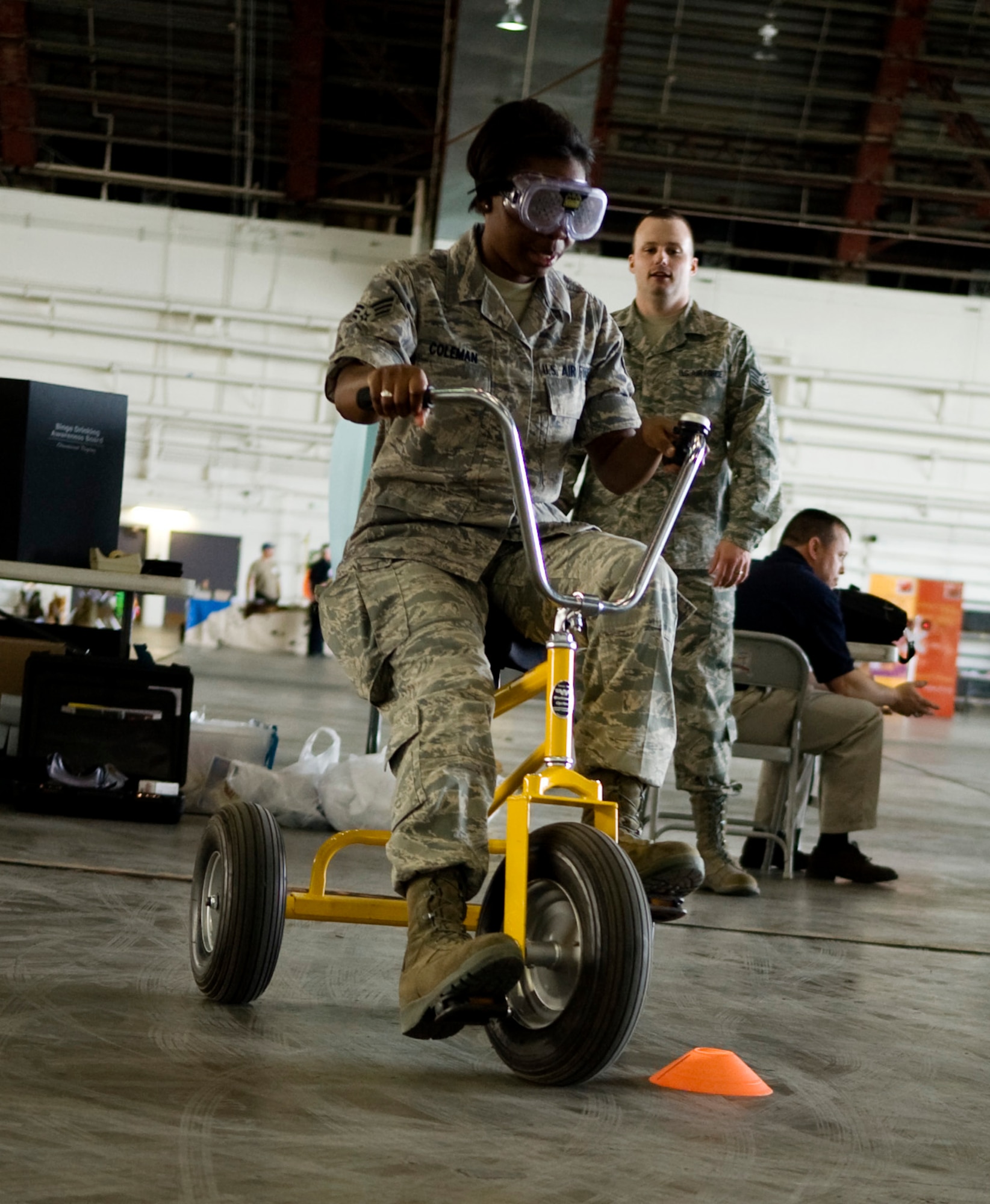 Senior Airman Rachelle Coleman navigates past cones on a tricycle during the annual summer safety fair May 26, 2011, Eielson Air Force Base, Alaska. Airmen assigned to the Alcohol and Drug Abuse Prevention and Treatment program provided fatal vision goggles to simulate driving under the influence on a closed course. Airman Coleman is a journalist assigned to the 354th Public Affairs office. (U.S. Air Force photo/Airman 1st Class Laura Goodgame) 