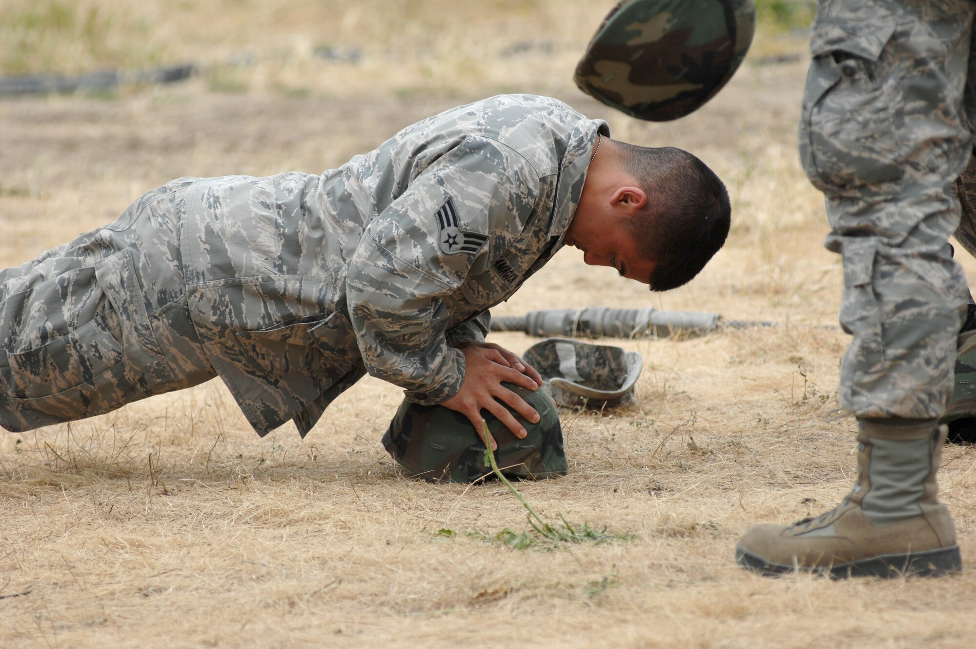 U.S. Air Force Senior Airman Marcello Yamaguchi, 446th Aeromedical Evacuation Squadron, Joint Base Lewis-McChord, Wash., performs a push-up using a helmet at Fort Hunter Liggett, Calif., May 16, 2011, in support of Global Medic 2011 and Warrior 91 11-01. Global Medic is a joint field training exercise for theater aeromedical evacuation system and ground medical components designed to replicate all aspects of combat medical service support. Warrior Exercise gives participating units an opportunity to rehearse military maneuvers and tactics such as security, convoy operations and quick reaction drills during simulated enemy attacks. (U.S. Air Force photo by Senior Airman Raymond A. Estes/Released)