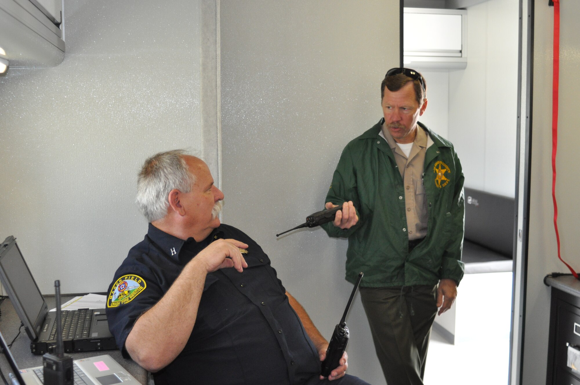 Deputy Sherriff Jay Edge (left), County of Los Angeles Sheriff's Department, talks with Capt. Scott Carpenter, March Air Reserve Base Fire Department, at the 3rd Annual Riverside County Multi-Agency Communication Interoperability Test at the Ben Clark Training Center in Riverside, Calif., May 19, 2011.  The test, nicknamed "Radio Rodeo," ensures city, county, state and federal first responder agencies will be able to work together during a major disaster.  (U.S. Air Force photo/ Megan Just)
