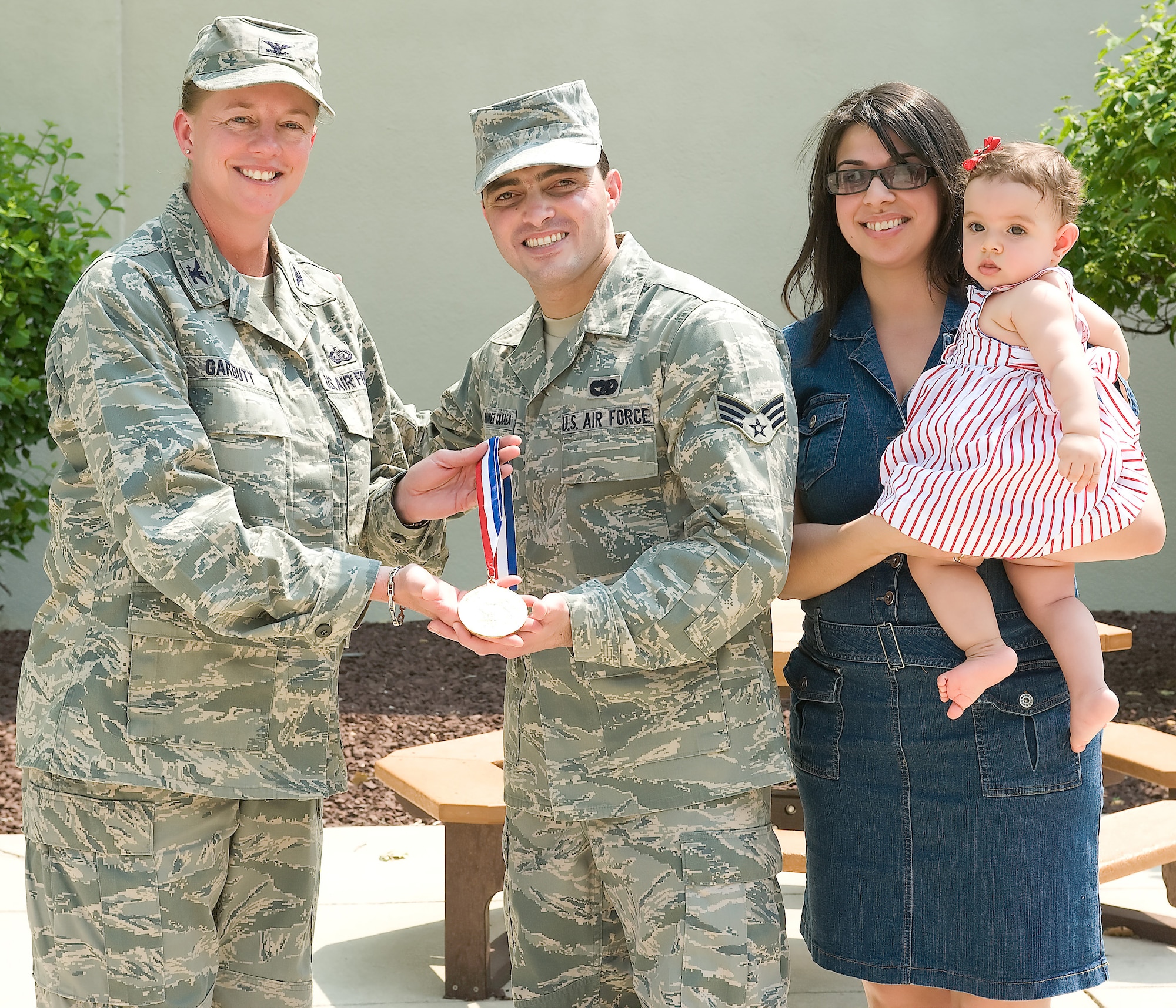Col. Joan Garbutt(left), 436th Mission Support Group, accepts a 2010 Pan-American Judo Championship’s gold medal on behalf of the base from Senior Airman  Geanni Hernandez-Quiala, 436th Aerial Port Squadron, and his wife Dania, May 26, 2011 at the Fitness Center Dover Air Force Base, Del.  Airman Hernandez-Quiala donated the medal to inspire servicemembers. (U.S. Air Force photo by Steve Kotecki)