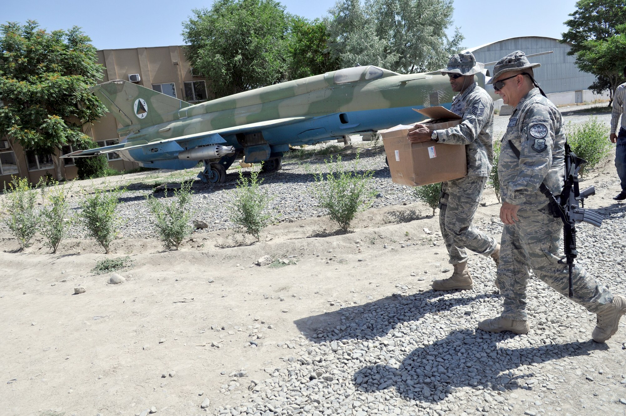 Master Sgt. Dion Bullock carries a box of Nomex fire-protection hoods while walking with Master Sgt. Edward Nowak to the Afghan air force fire fighting training complex May 28, 2011, in Kabul, Afghanistan. The Nomex hoods were donated by the Robeson County Firefighters Association in Parkton, N.C. Sergeant Bullock is a 738th Air Expeditionary Advisory Squadron firefighter adviser and Sergeant Nowak is a 440th Air Expeditionary Advisory Squadron C-27 production superintendent adviser and volunteer firefighter. (U.S. Air Force photo/Tech. Sgt. Brian E. Christiansen)