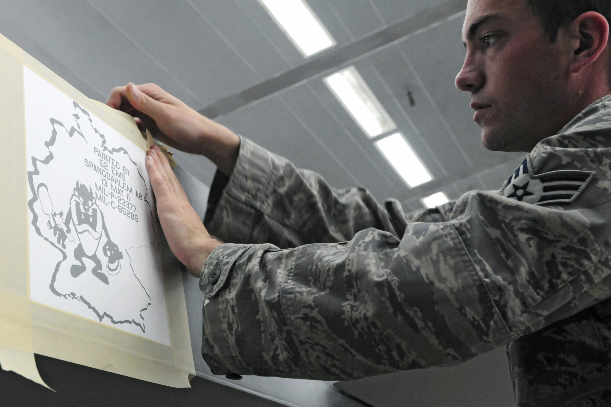 SPANGDAHLEM AIR BASE, Germany – Senior Airman Erik Bouse, 52nd Equipment Maintenance Squadron aircraft structural maintenance journeyman, applies a stencil to an F-16 Fighting Falcon before painting the jet here May 13. The 52nd EMS fabrication flight works to prevent corrosion on support equipment and aircraft-related parts.  (U.S. Air Force photo/Airman 1st Class Matthew B. Fredericks)
