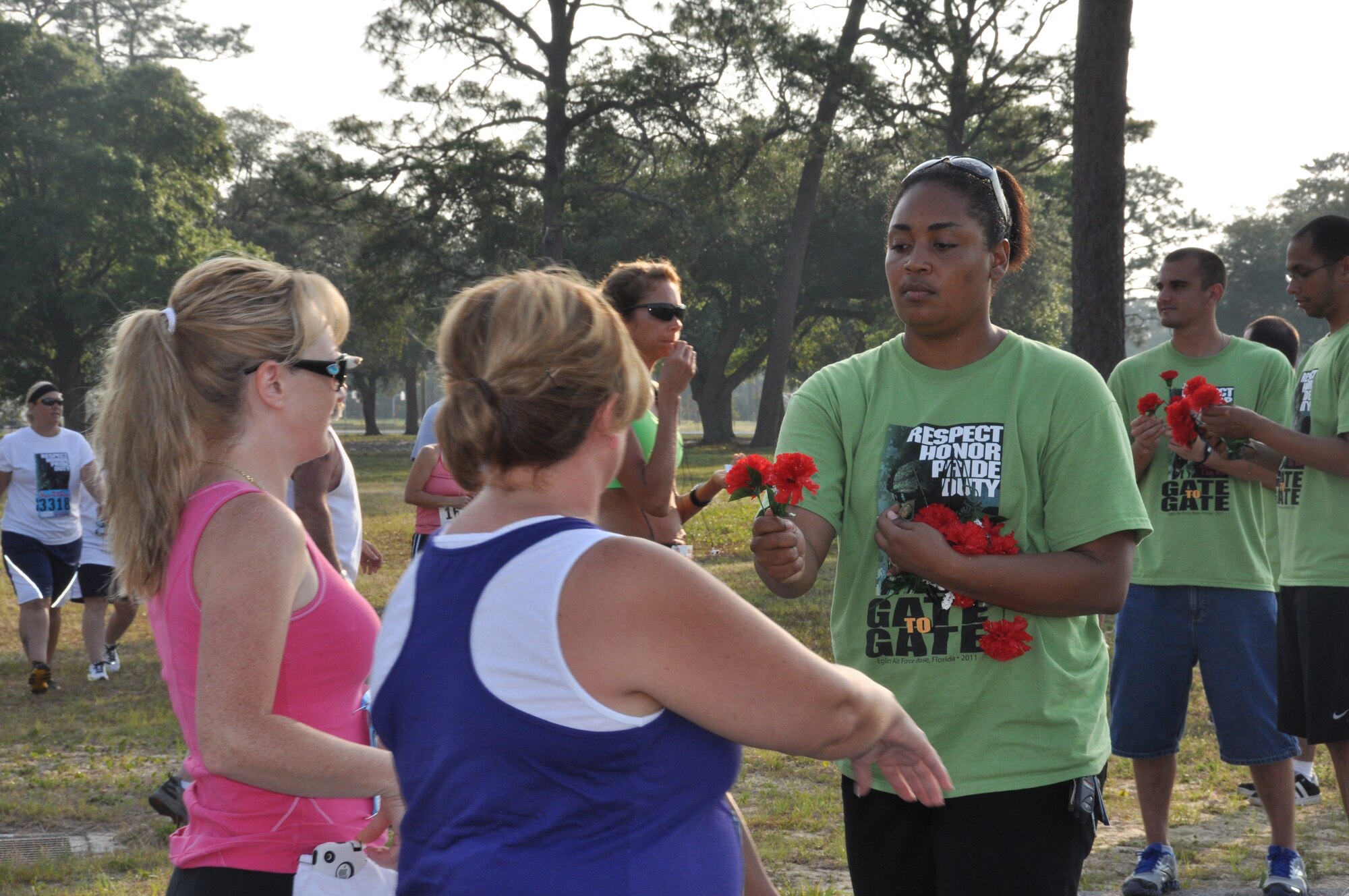 Staff Sgt. Aundrea Minns of the Eglin Fitness Center hands out carnations prior to the start of base 26th Annual Gate-to-Gate Run. Race participants and guests drop flowers at the All Veterans Memorial in honor of those who served during the tradional event. The Memorial Day run drew 1,939 participants. (U.S. Air Force photo/Chrissy Cuttita)