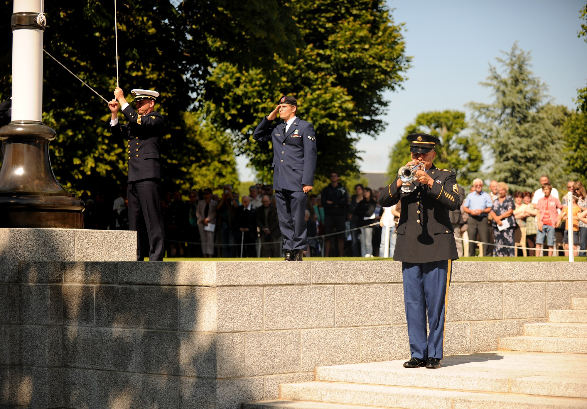 SAINT JAMES, France – U.S. Army Sgt. 1st Class David Martinez, U.S. Army Europe Band trumpeter, plays Taps as a French Sailor raises the U.S. flag during a memorial ceremony at Brittany American Cemetery and Memorial in Saint James, France, May 29. Brittany American Cemetery is the final resting place for 4,410 U.S. service members who died during the Normandy and Brittany campaigns of World War II in 1944. (U.S. Air Force photo/Senior Airman Nathanael Callon)