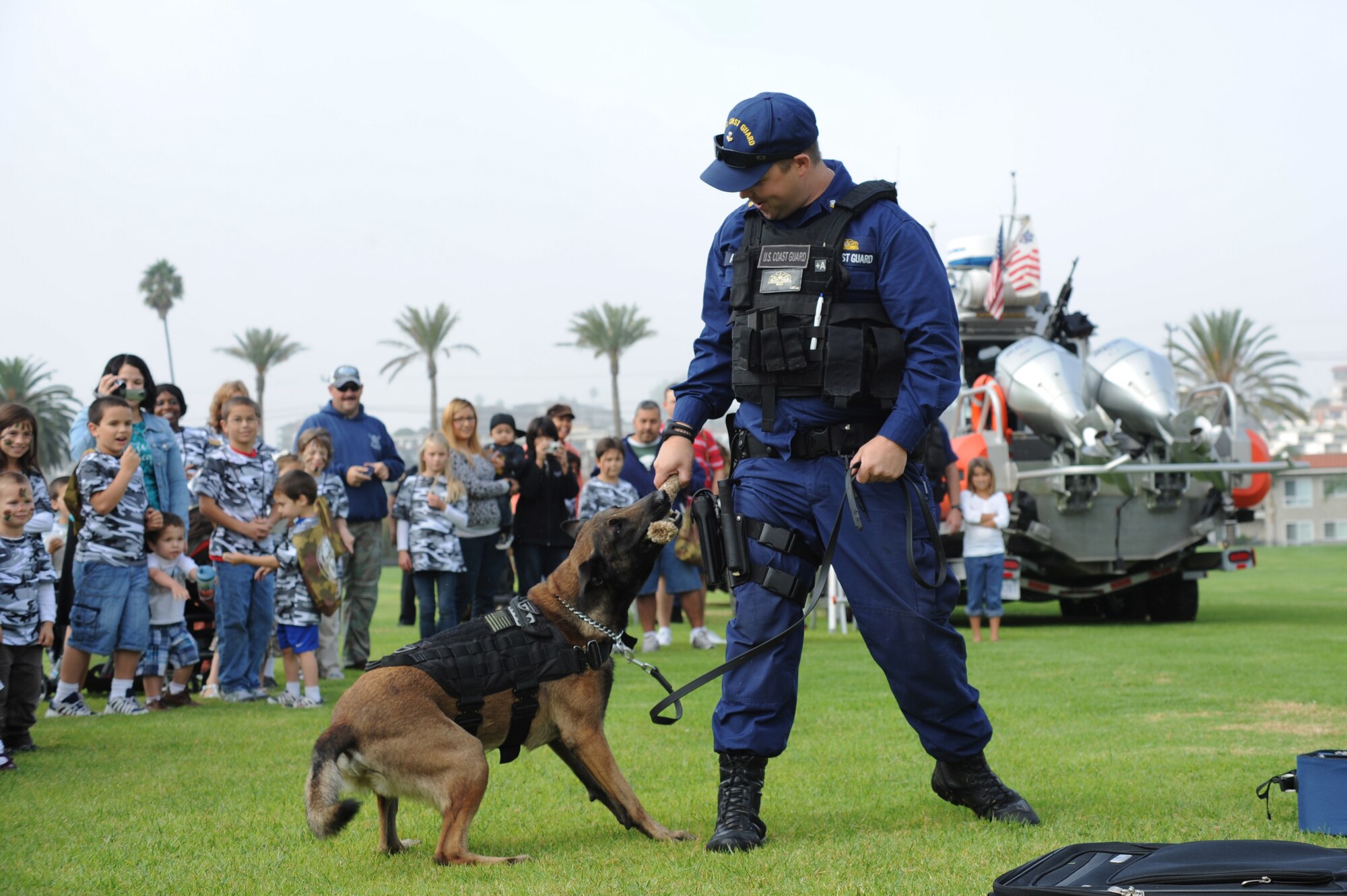 US Coast Guard Petty Officer Second Class Nick Antis, a member of US Coast Guard Maritime Safety & Security Team (MSST) 91103, Long Beach, Calif., rewards Ryder, a bomb-sniffing dog assigned to the team after successfully detecting a simulated hidden explosive at the annual Kids Understanding Deployment Operations (KUDOS) event at Fort MacArthur in San Pedro, Calif., Oct. 22, 2011.  KUDOS is a military and youth interaction program sponsored by the Airman & Family Readiness Center at Los Angeles Air Force Base in El Segundo, Calif., and is designed to give children a taste of what deployment is like.  The children ages five to 15 pass through a mobility line, interact with displays and engage in military-inspired activities throughout the event. (Photo by Sarah Corrice)