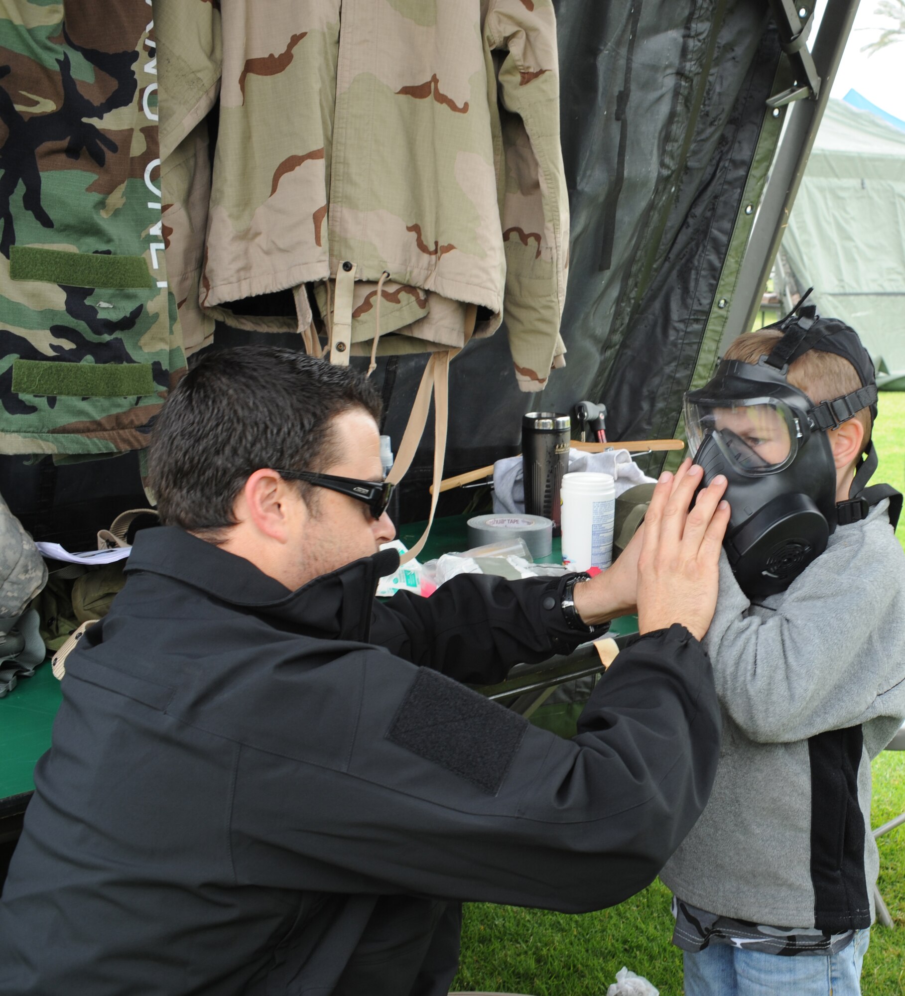 Justin Diedolf, 61st Air Base Group Emergency Manager at Los Angeles Air Force Base, Calif., assists a participant with properly fitting his gas mask at the annual Kids Understanding Deployment Operations event at Fort MacArthur in San Pedro, Calif., Oct. 22, 2011. KUDOS is a military and youth interaction program
sponsored by the Airman & Family Readiness Center at Los Angeles Air Force
Base in El Segundo, Calif., and is designed to give children a taste of what
deployment is like.  The children ages five to 15 pass through a mobility line,
interact with displays and engage in military-inspired activities throughout
the event. (Photo by Sarah Corrice)