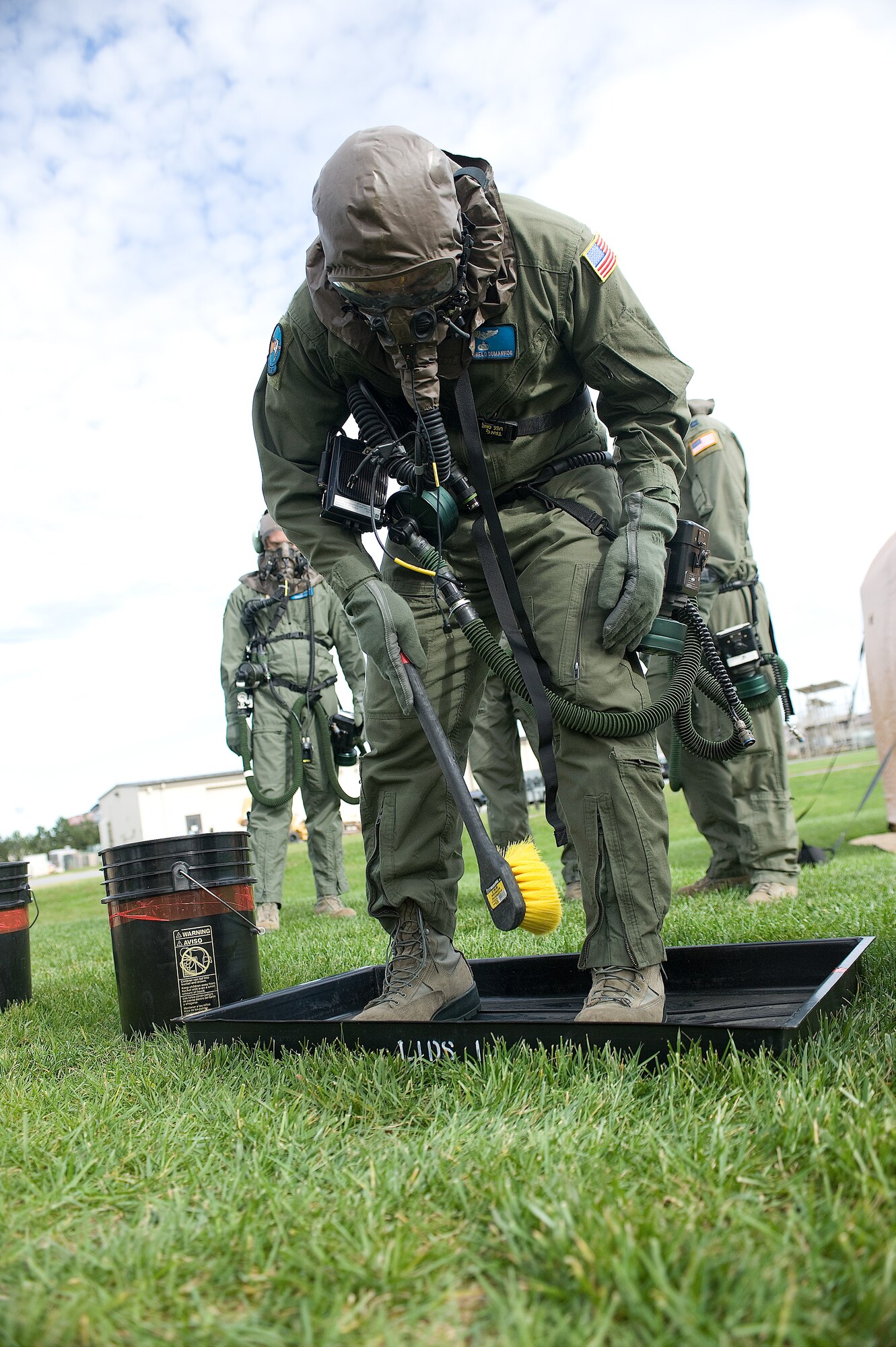Staff Sgt. Angelo Dumanhog, a loadmaster with the 9th Airlift Squadron, brushes simulated contamination from his flight suit and boots during an exercise Oct. 28, 2011, at Dover Air Force Base, Del., to prepare for the Operational Readiness Inspection in December. Team Dover is preparing by going through scenarios that might present themselves during the ORI. (U.S. Air Force photo by Steve Kotecki)