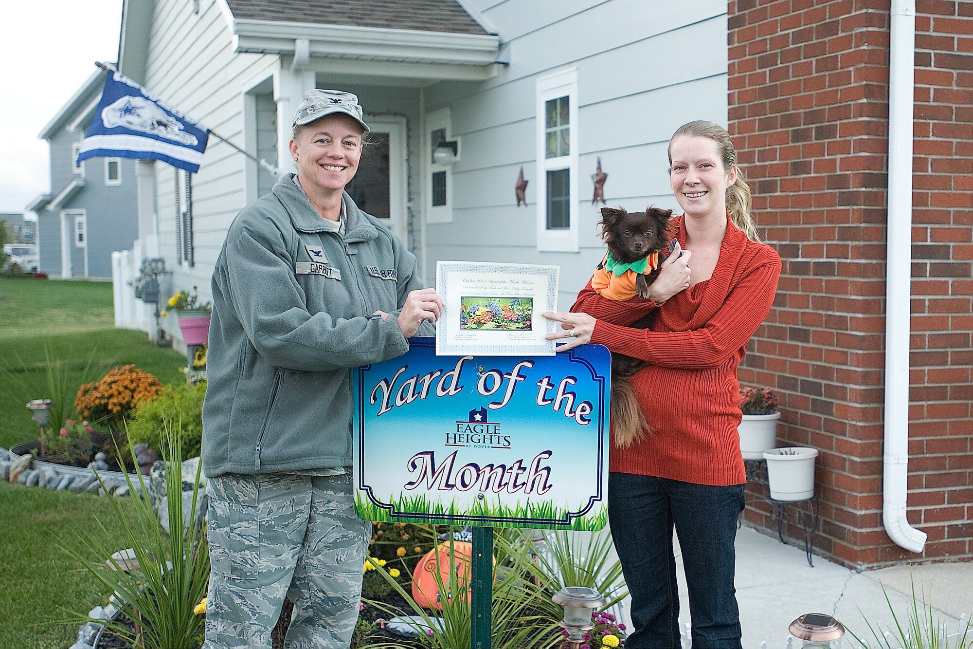 Col. Joan Garbutt, left, commander of the 436th Mission Support Group, stands with Ashley Kennedy and her dog Dallas, recognizing them as Blue Heron Breeze Yard of the Month winners for October at Dover Air Force Base, Del. (U.S. Air Force photo by Airman 1st Class Samuel Taylor)

