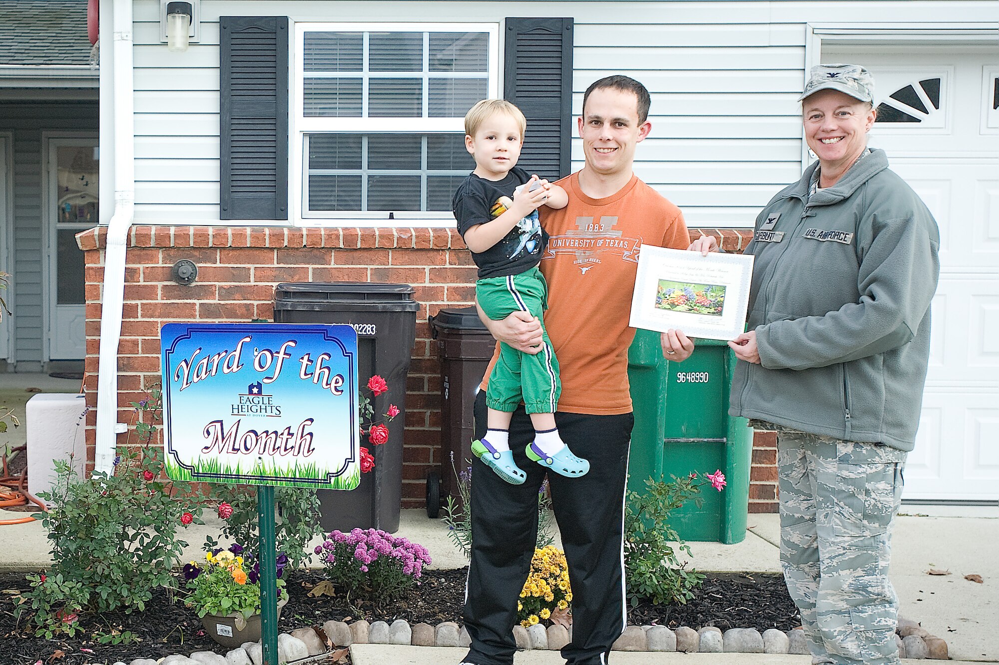 Col. Joan Garbutt, right, commander of the 436th Mission Support Group, stands with Jesse Kot and his son Matthew, recognizing them as Oriole’s Cove Yard of the Month winners for October at Dover Air Force Base, Del. (U.S. Air Force photo by Airman 1st Class Samuel Taylor)

