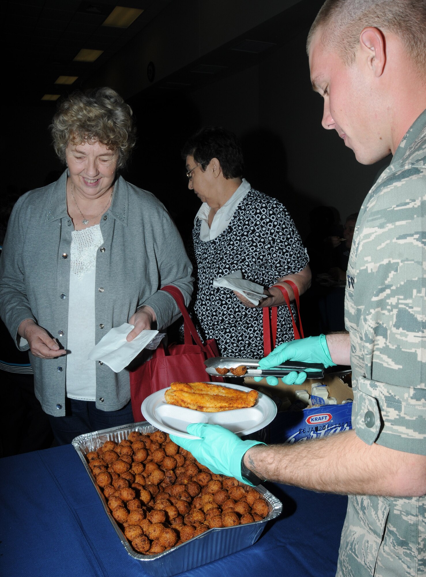 Left, L.C. Rausch, retired Air Force, of Perkiston, Miss., and Betty Partin, dependent of retired Air Force member, Charles Partin, stand in line to be served fried fish and hush puppies by Airman Basic Daniel Taylor, 335th Training Squadron student, during Retiree Appreciation Day Oct. 28, 2011, at the Roberts’ Consolidated Aircraft Maintenance Facility at Keesler Air Force Base, Miss.  The annual event included door prizes, more than 30 displays with information pertinent to retirees, a guest speaker and a free lunch.  (U.S. Air Force photo by Kemberly Groue)