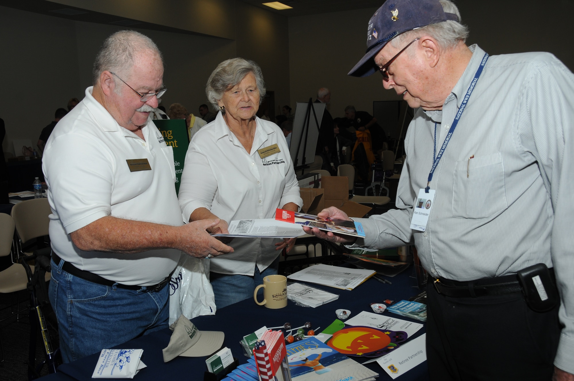 John and Mabel Cole offer pamphlets and other literature on the Mississippi Gulf Coast Retiree Partnership program to Ken Schneider during Retiree Appreciation Day Oct. 28, 2011, at the Roberts’ Consolidated Aircraft Maintenance Facility at Keesler Air Force Base, Miss.  A key note speaker from the National Associations for Uniformed Services, could be heard during the annual event.  Schneider is retired Navy and a member of the Armed Forces Retirement Home in Gulfport, Miss.  (U.S. Air Force photo by Kemberly Groue)