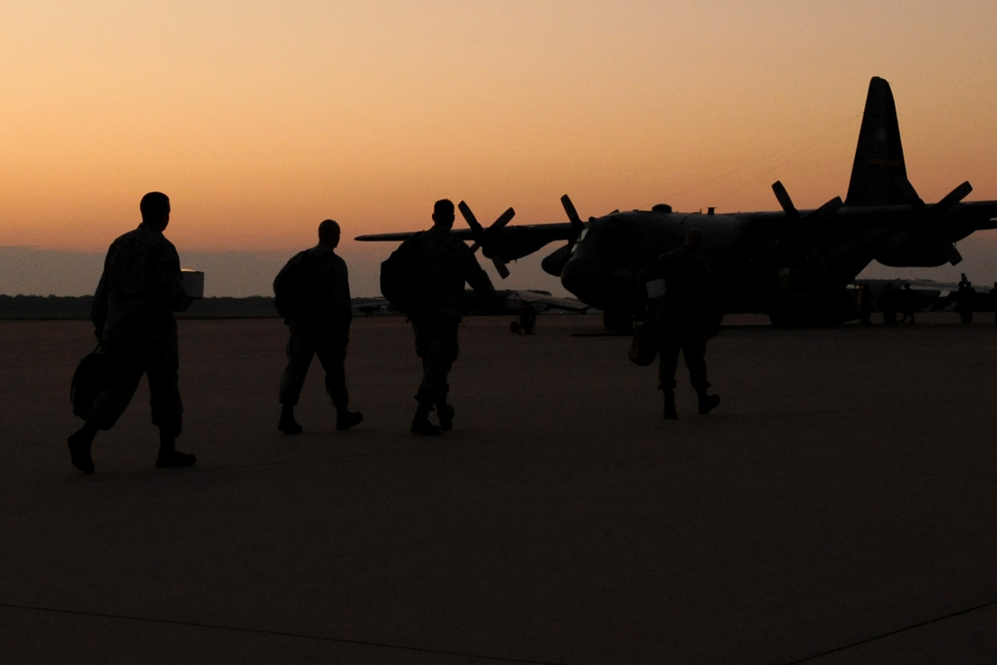 The sun rises on a group of 917th Fighter Group personnel as they walk toward an awaiting C-130 Hercules at Barksdale Air Force Base, La., Sept. 21, 2011. The personnel are assigned to the 917th Maintenance Squadron and deployed to an unknown location in support of Operation Enduring Freedom. (U.S. Air Force photo by Master Sgt. Greg Steele/Released)