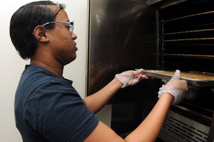 Petty Officer 3rd Class Ashley Shaw places a sweet potato bread mixture into the oven to bake at the Joint Base Charleston-Air Base Child Development Center. Shaw and other Sailors work at the CDC helping prepare meals for all the children while waiting on orders for their next school assignment. (U.S. Navy photo/Petty Officer 1st Class  Jennifer  Hudson)