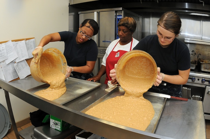 Melissa Gaines supervises Petty Officer 3rd Class Ashley Shaw (left) and Heather Isham as they pour a batter of sweet potato bread onto cooking pans. The Sailors are working at the Joint Base Charleston – Air Base Child Development Center while waiting for orders to their next school assignment.  (U.S. Navy photo/Petty Officer 1st Class Jennifer Hudson)