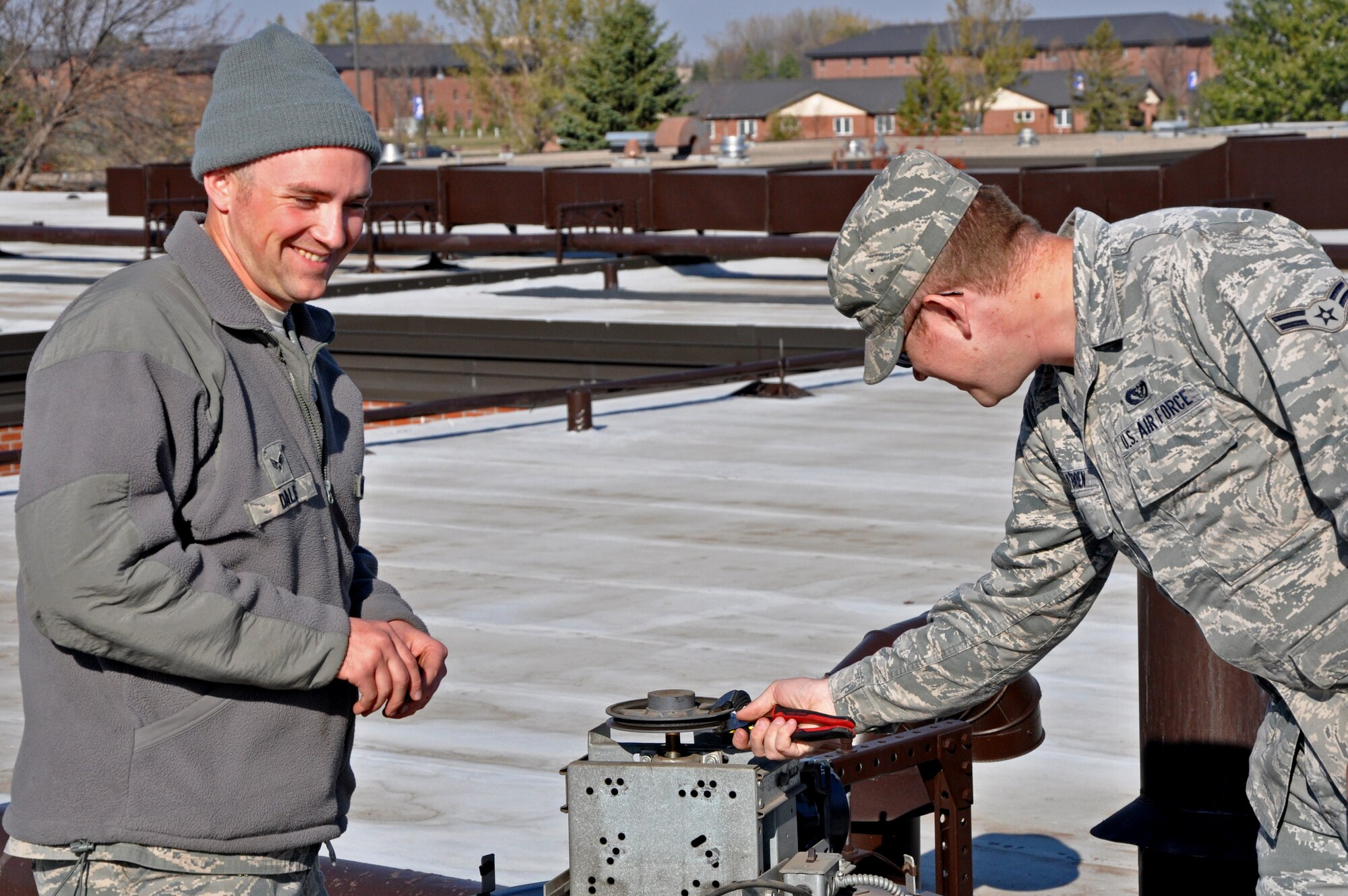 Senior Airman Casey Dale (left), 319th Civil Engineer Squadron, works on the roof of the 319th Air Base Wing Medical Facility with Airman 1st Class Kevin O'Brien, 319th CES, on Oct. 21 on Grand Forks Air Force Base, N.D. (U.S. Air Force photo/Airman 1st Class Derek VanHorn)