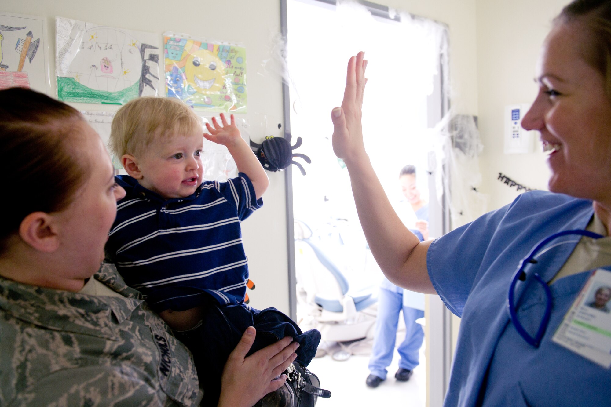 YOKOTA AIR BASE, Japan -- -- Maj. Stacey Zaikoski (right), 374th Dental Squadron pediatric dentist, and Matthew Nichols, 14 months, high-five after completing his first dental appointment at Yokota's dental clinic, Oct. 28, 2011. . Zaikoski said that the earlier the dental visit, the better the chance of preventing dental problems. (U.S. Air Force photo/Osakabe Yasuo)