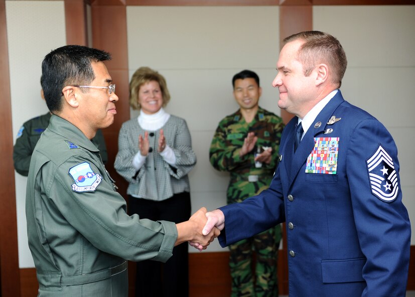 Lt Gen Lee (left), ROK Air Force Operations Commander, congratulates 7th Air Force Command Chief Master Sergeant Tom L. Baker for outstanding contributions to the ROK-US alliance during a ceremony held Nov. 1. Lt Gen Lee presented Command Chief Baker(right) with a letter of commendation and plaque from the ROKAF as Command Chief Baker's wife, Mrs. Peggy Baker, CMSgt Byun, Wang Sung AFOC Command Chief watched on.