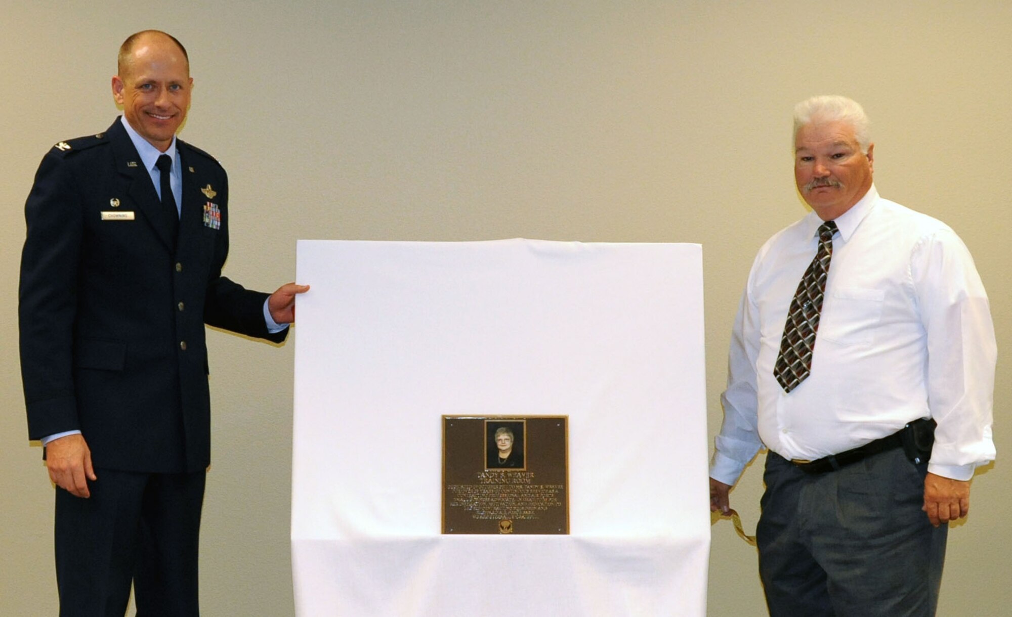 Col. Scott Chowning and Mr. David Weaver unveil a plaque dedicating a 82nd Contracting Squadron training room to Mrs. Tandy Weaver, Oct. 19, 2011. Weaver, former 82nd CONS Director of Business Operations, worked for the Air Force as a civilian for over 27 years and was responsible for bringing in over $110 million to Sheppard through various programs. (U.S. Air Force photo/Joshua Wilson)