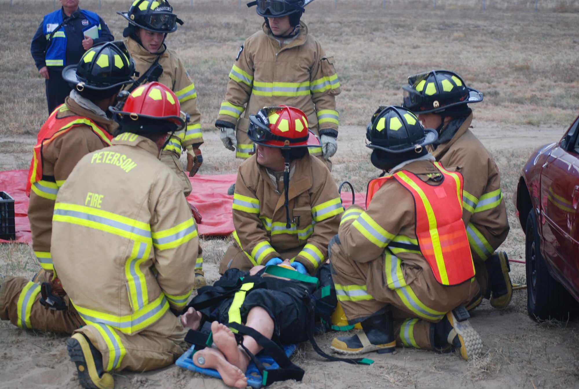 Personnel from the Peterson fire department administer medical care to an individual who was trapped under a vehicle during an exercise scenario Oct. 26, 2011. The entrapment exercise was one of several smaller scenarios to evaluate response to the wing’s existing emergency plans. (U.S. Air Force photo/Lea Johnson)
