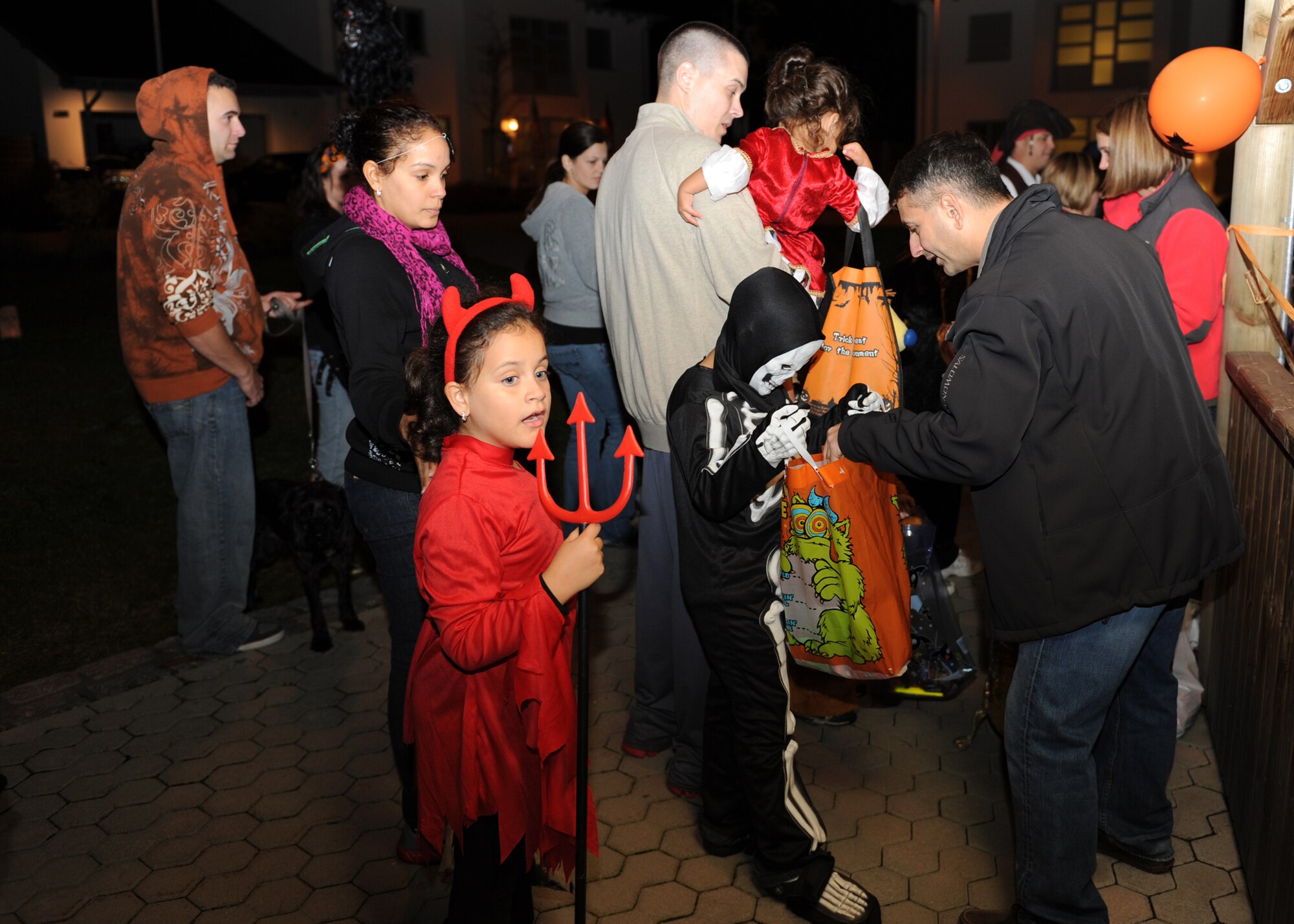 SPANGDAHLEM AIR BASE, Germany – Col. David Julazadeh, 52nd Fighter Wing vice commander, right, hands out candy to families during a trick-or-treat event in base housing during Halloween here Oct. 31. Trick-or-treating was held on base for Airmen and their families so they could enjoy the U.S. holiday. (U.S. Air Force photo/Senior Airman Christopher Toon)
