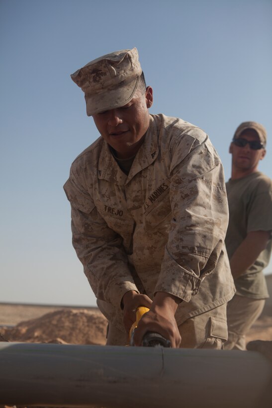 Lance Cpl. Jimmy Trejo cuts a piece of conduit that will protect underground fiber optic cable at Camp Dwyer, Afghanistan, Nov. 3.  Trejo, from Van Buren, Ark., works as a wireman for Marine Wing Communications Squadron 28.